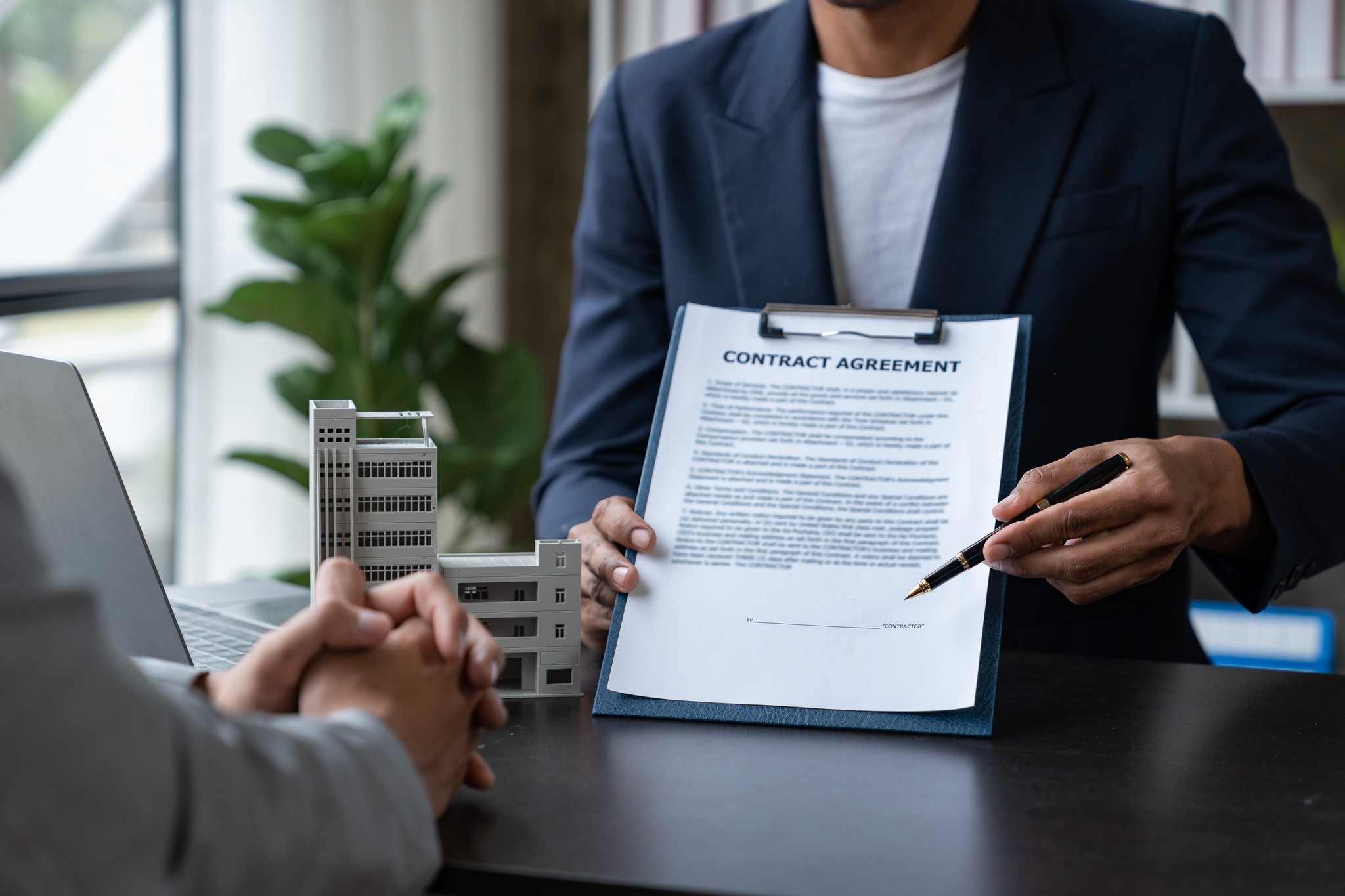 A winding road cuts through rocky terrain, surrounded by patches of green grass and illuminated by sunlight.