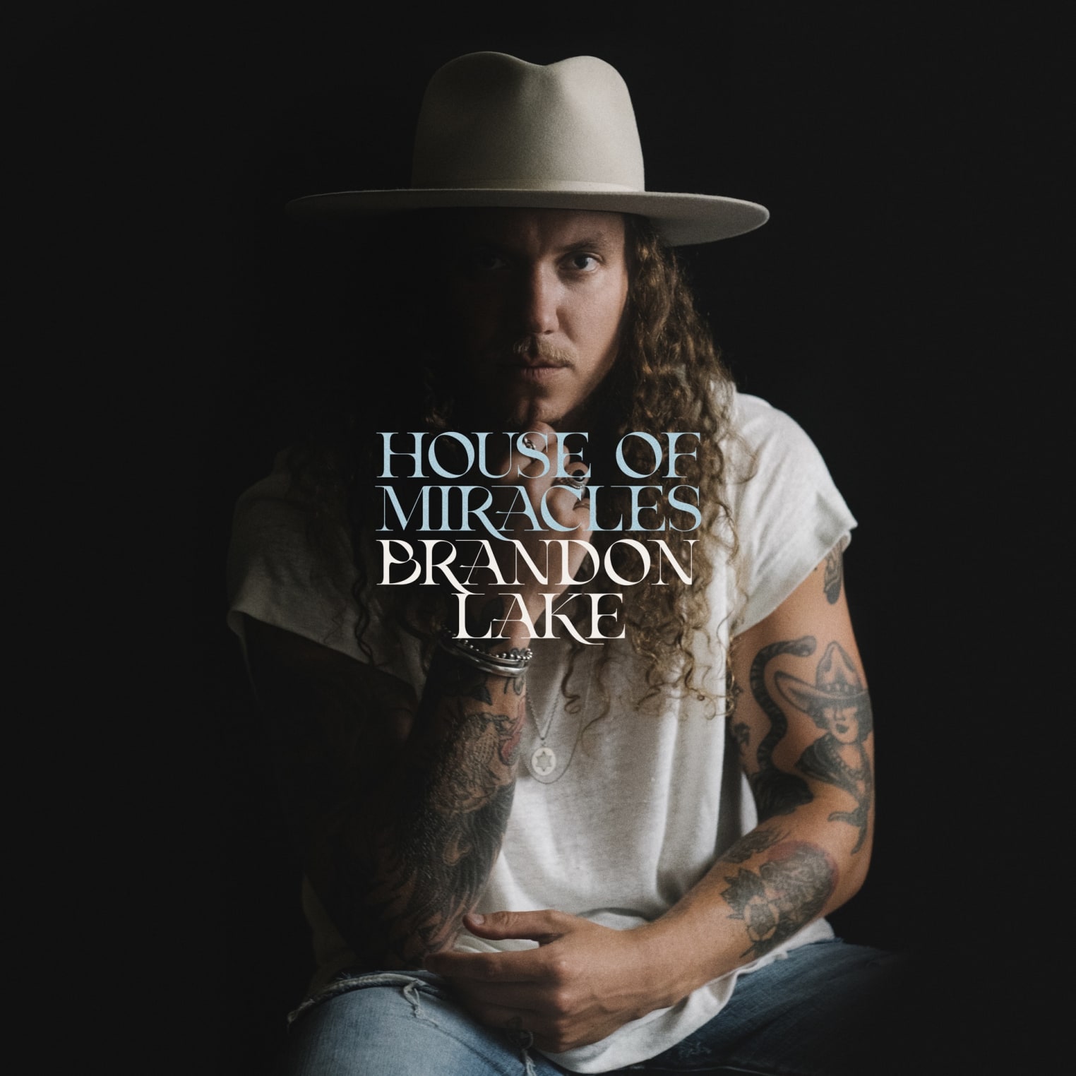 Album artwork for "Gratitude" by Brandon Lake: a man with long curly hair, tattoos, and wide-brimmed hat sits against a dark background. Text: House of Miracles, Brandon Lake.