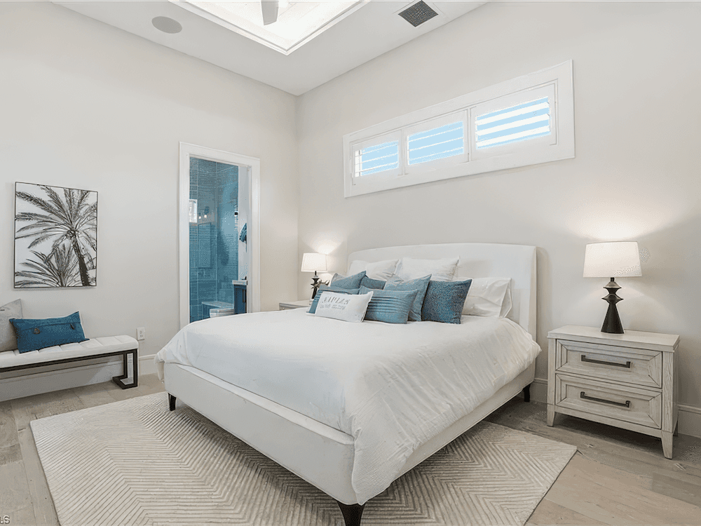 a large bedroom with high ceilings and a large white bed