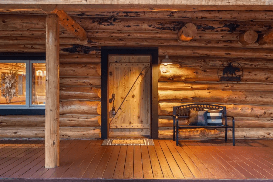Log cabin entrance with a wooden door and bench.