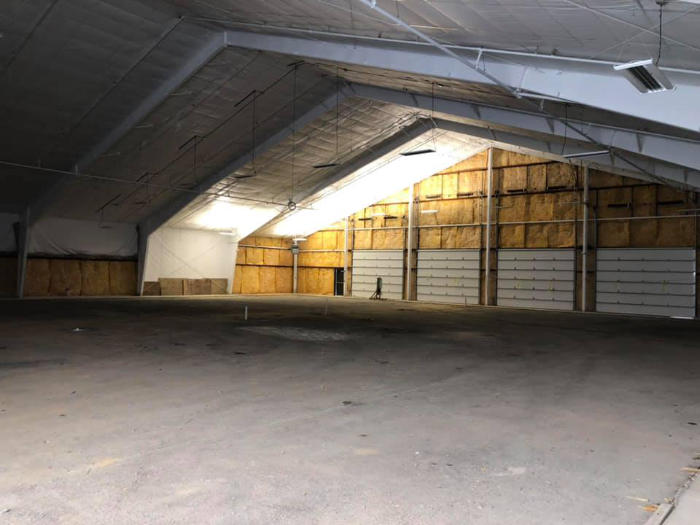 Interior of a spacious building with a high ceiling and warm lighting, showcasing a bare concrete floor.