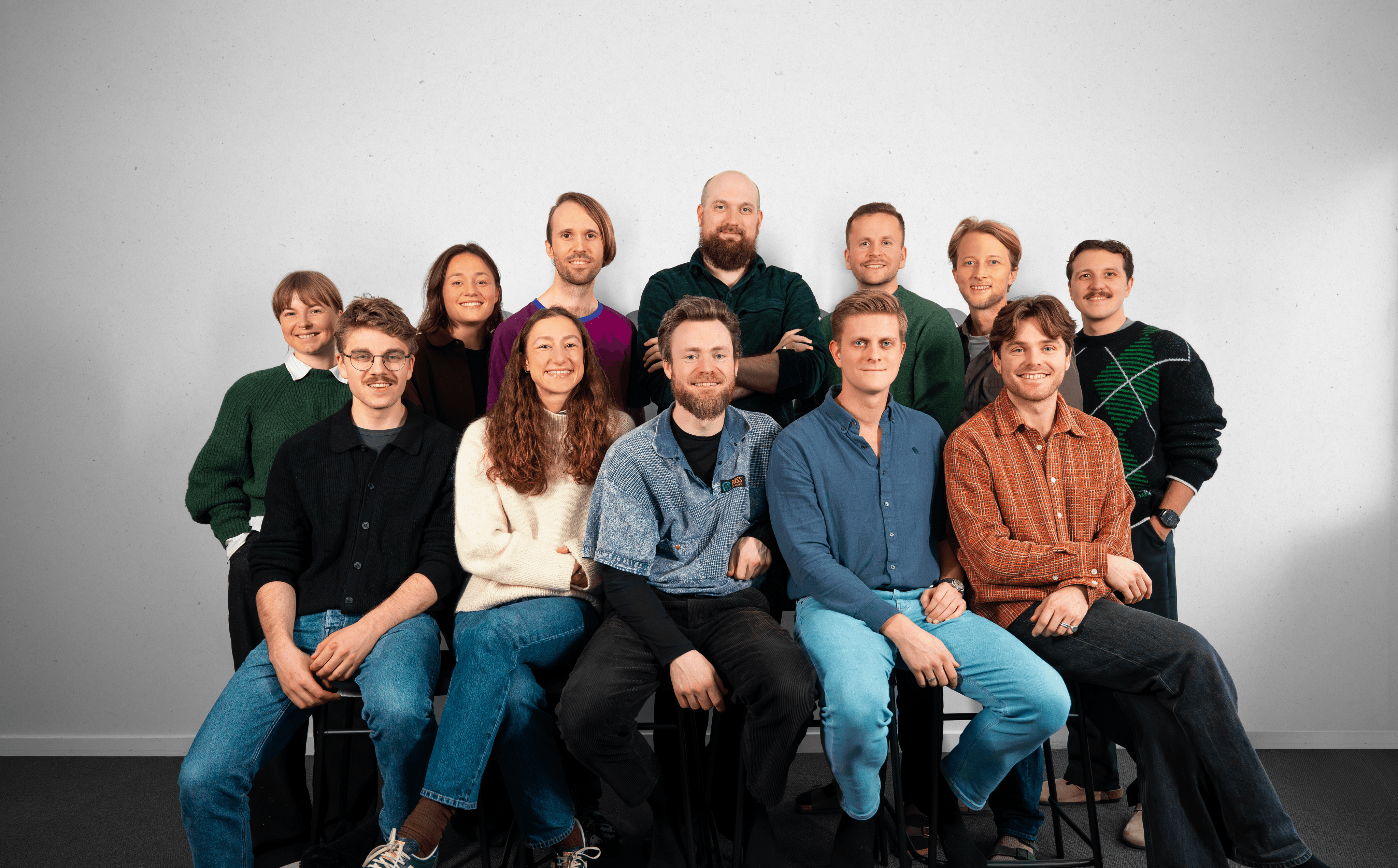 men and women sitting and standing by the table looking happy while staring at laptop