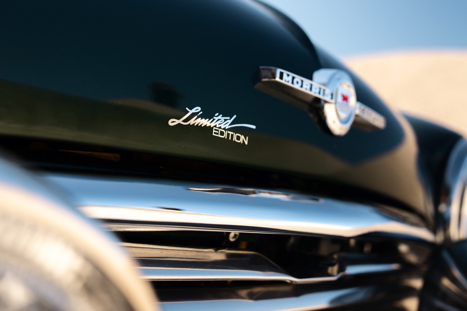 A small, green and black vehicle parked on a sandy surface, with a warm sunset lighting the scene.