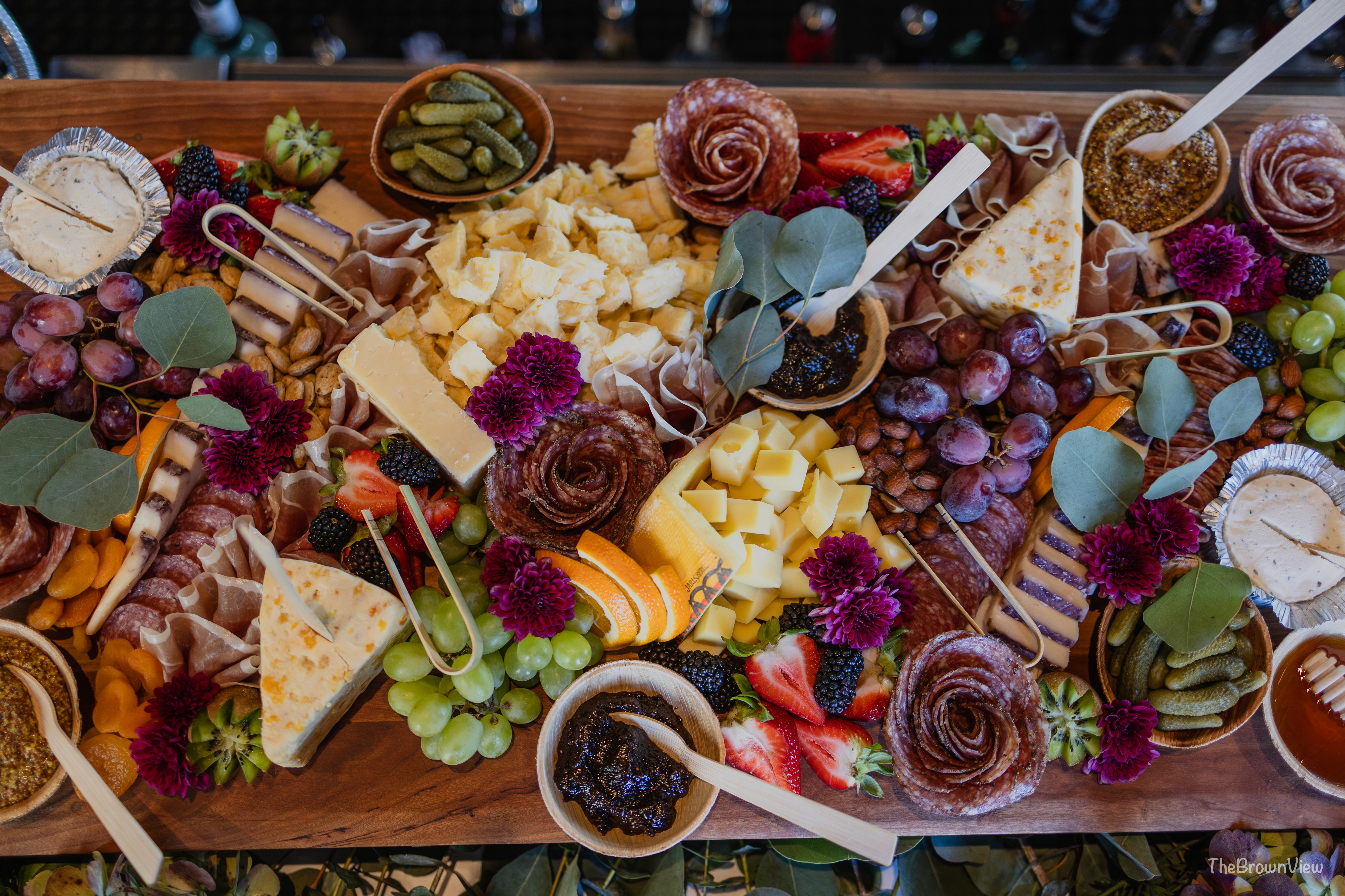 Luxury charcuterie spread with cheese, cured meats, fresh fruit, and gourmet accompaniments at an event.