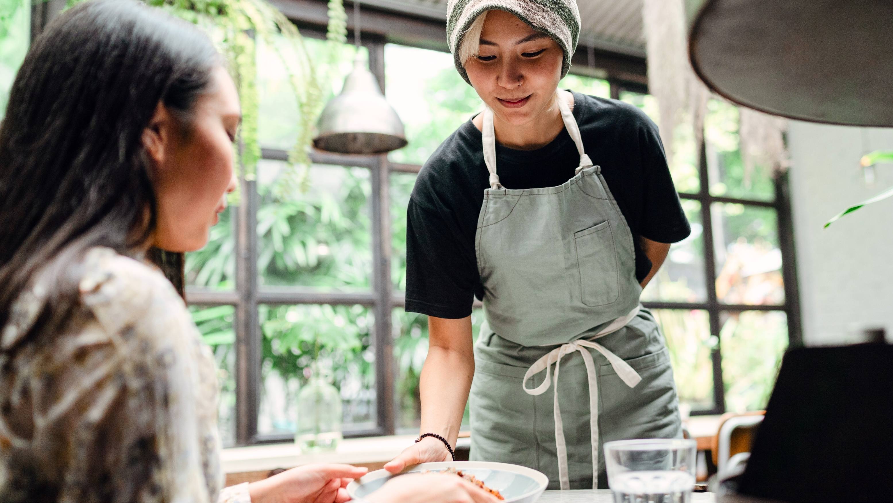 一名马来西亚服务员在咖啡馆为顾客上菜