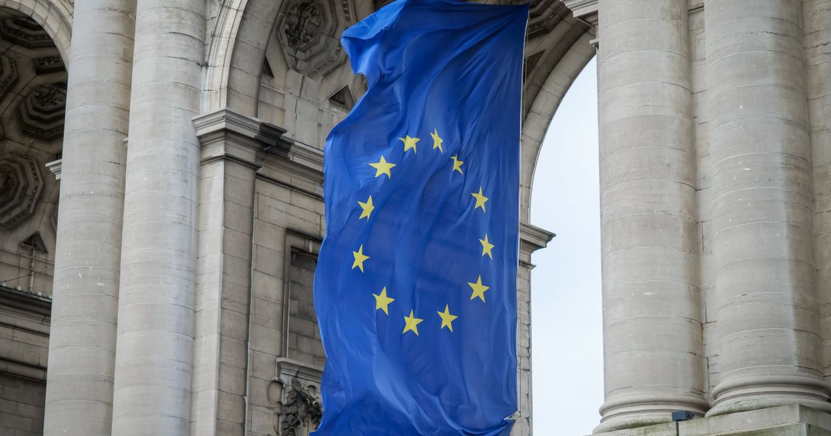 Drapeau de l'Union européenne flottant devant un bâtiment institutionnel en pierre