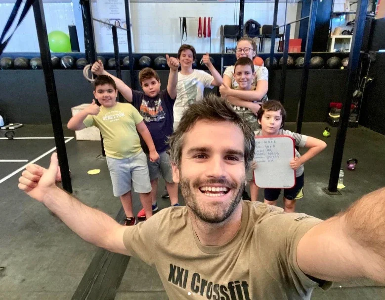 Selfie de um homem a fazer um fixe com crianças ao fundo