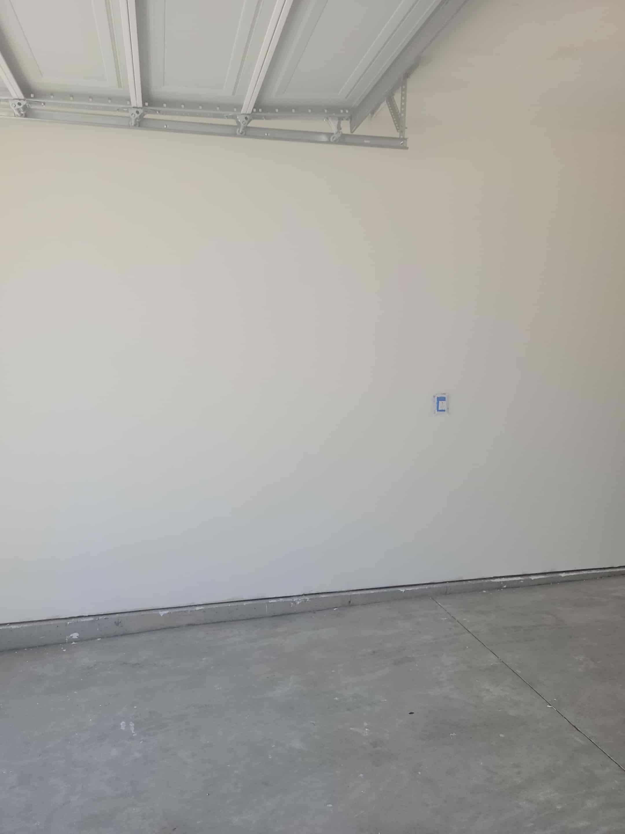 Empty room with light-colored walls and gray flooring, featuring a ceiling with exposed beams.