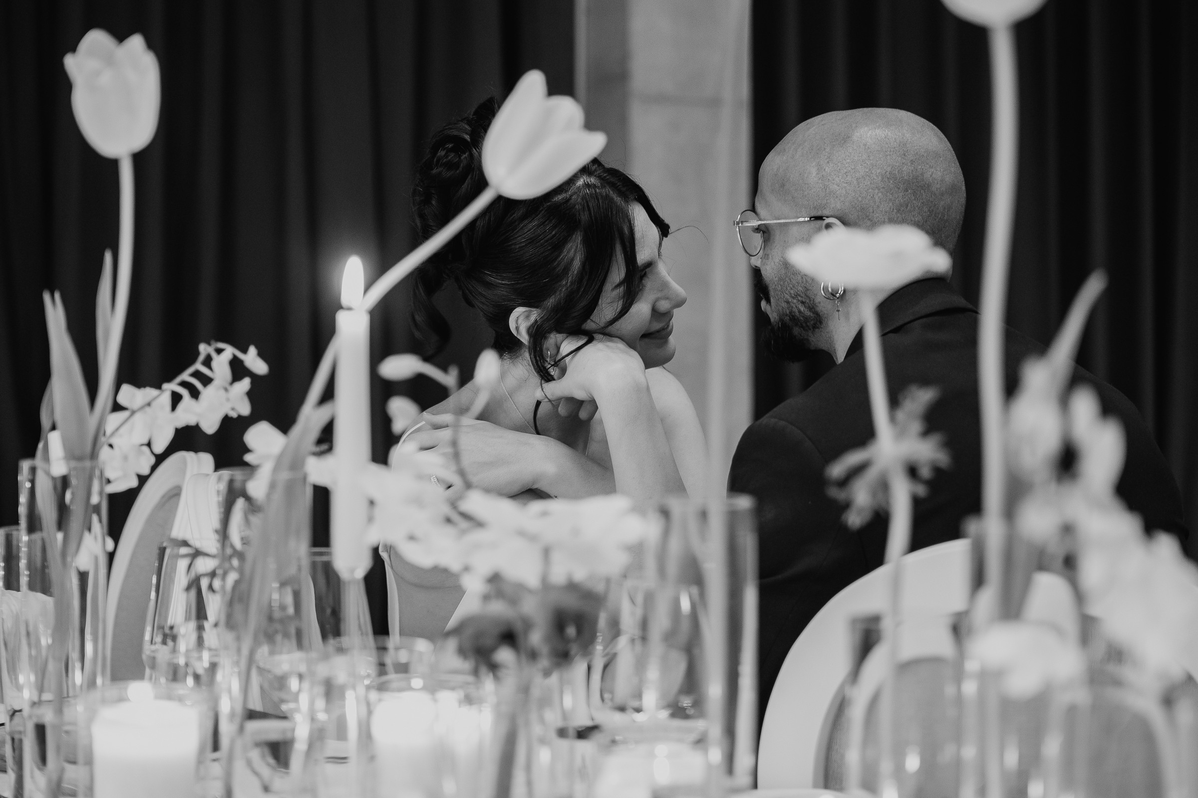 Brautpaar sitzt am Tisch und schaut sich lächelnd in die Augen.