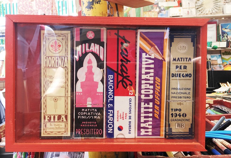 A wooden red box with a glass on a side, that contains some other rectangular colored boxes with text on them.