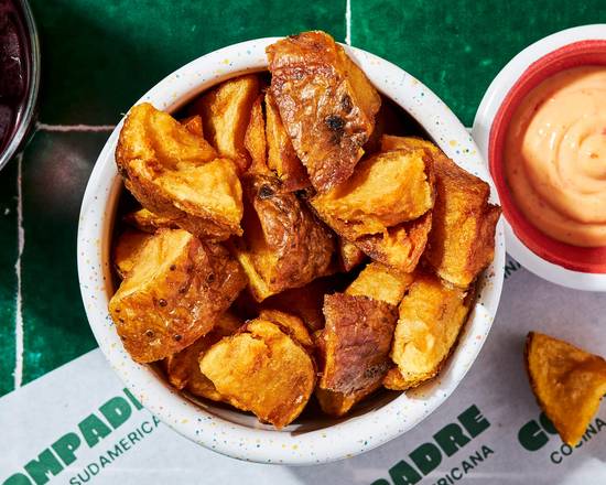 Papas Fritas du restaurant latino Compadre à Paris, pommes de terre dorées et croustillantes servies avec chicharrón de porc, sauce panela tamarin et salsa criolla. Une garniture street food typiquement sud-américaine