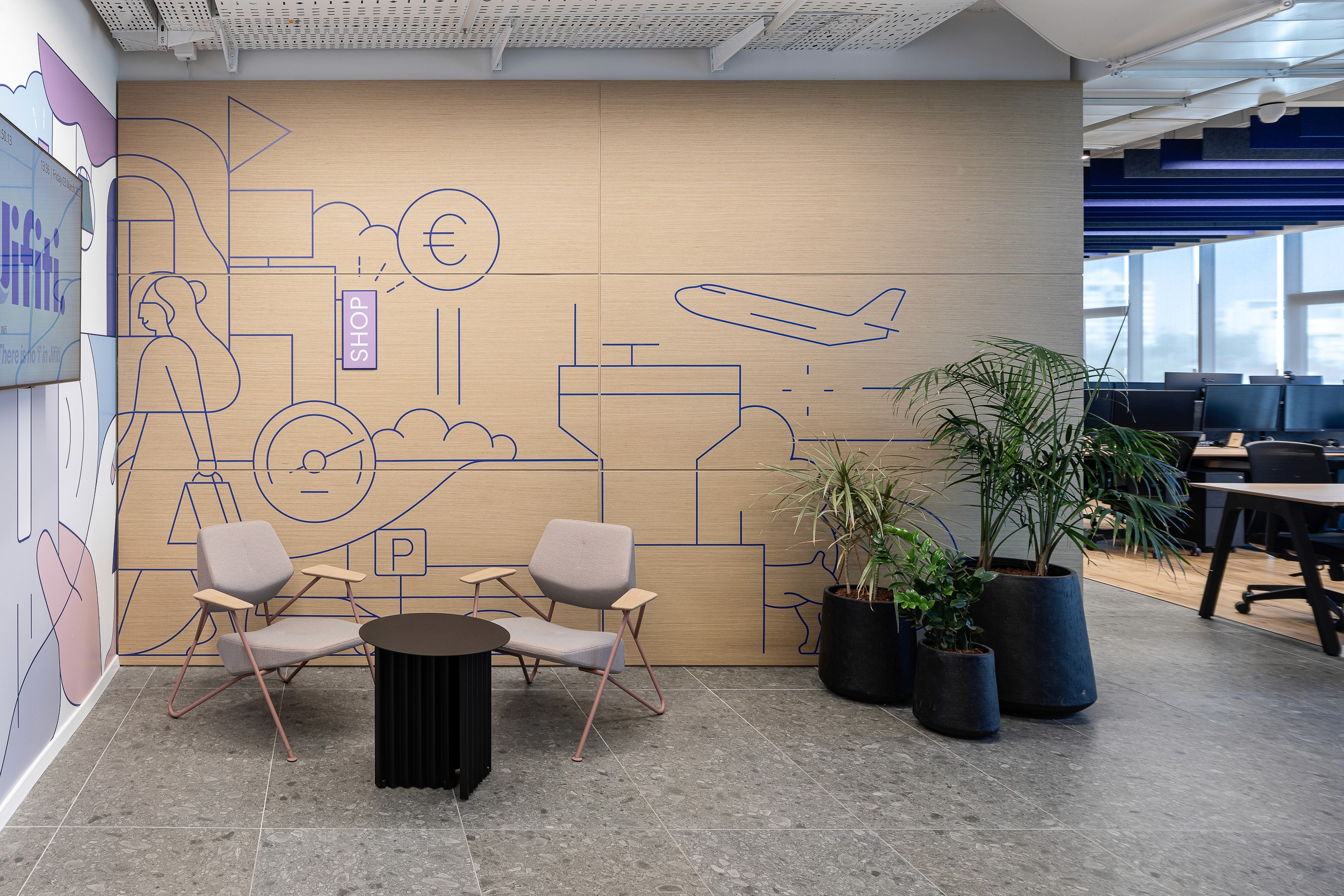 עיצוב חוויתי: פינת ישיבה לא-פורמלית על רקע קיר מאויר בנושא Fintech, המכניס צבע, הומור ואופי ייחודי לסביבת העבודה.