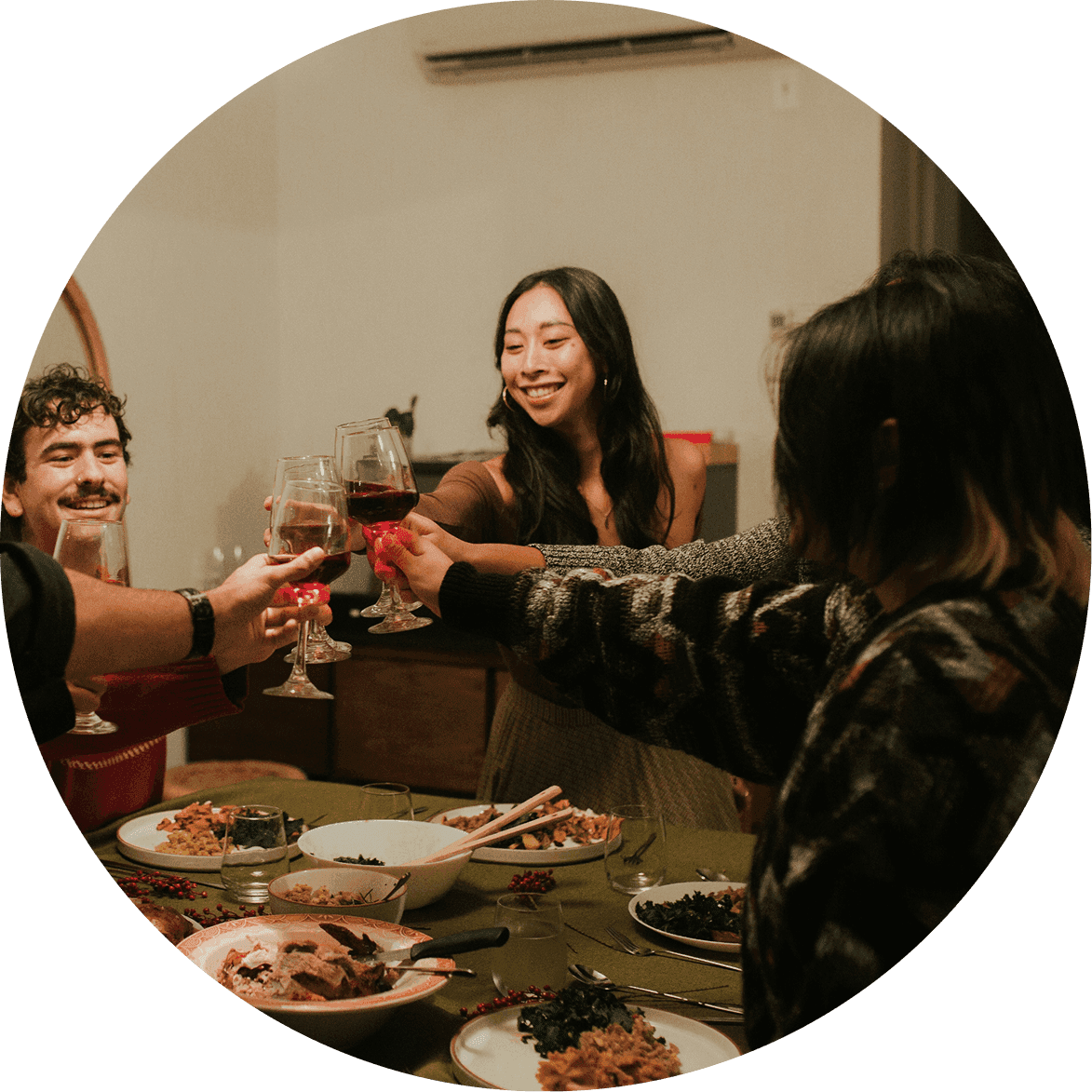 Group of friends gather around a dining table raising glasses in a toast