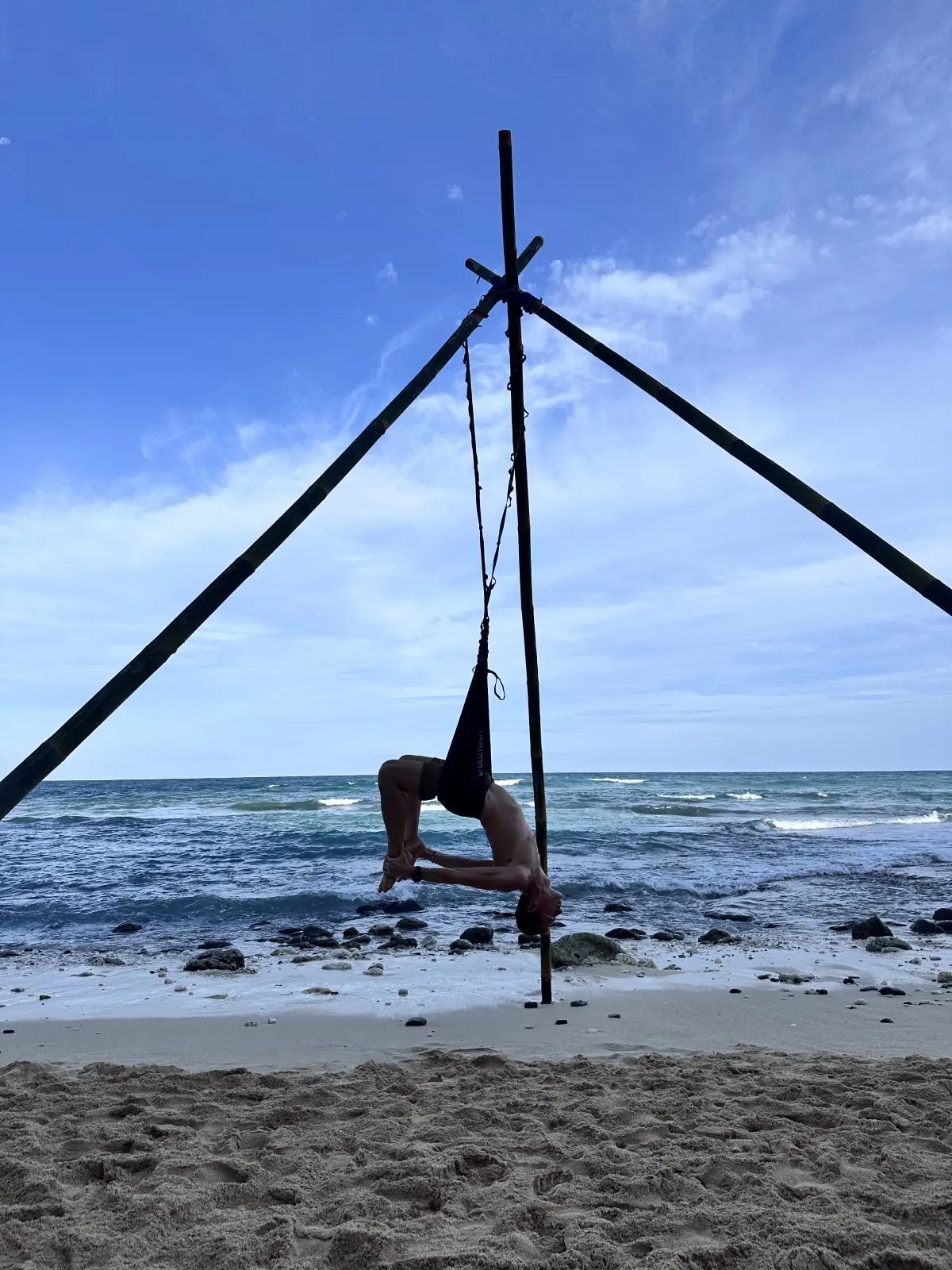 Male practitioner demonstrating aerial yoga strength and conditioning on outdoor rig