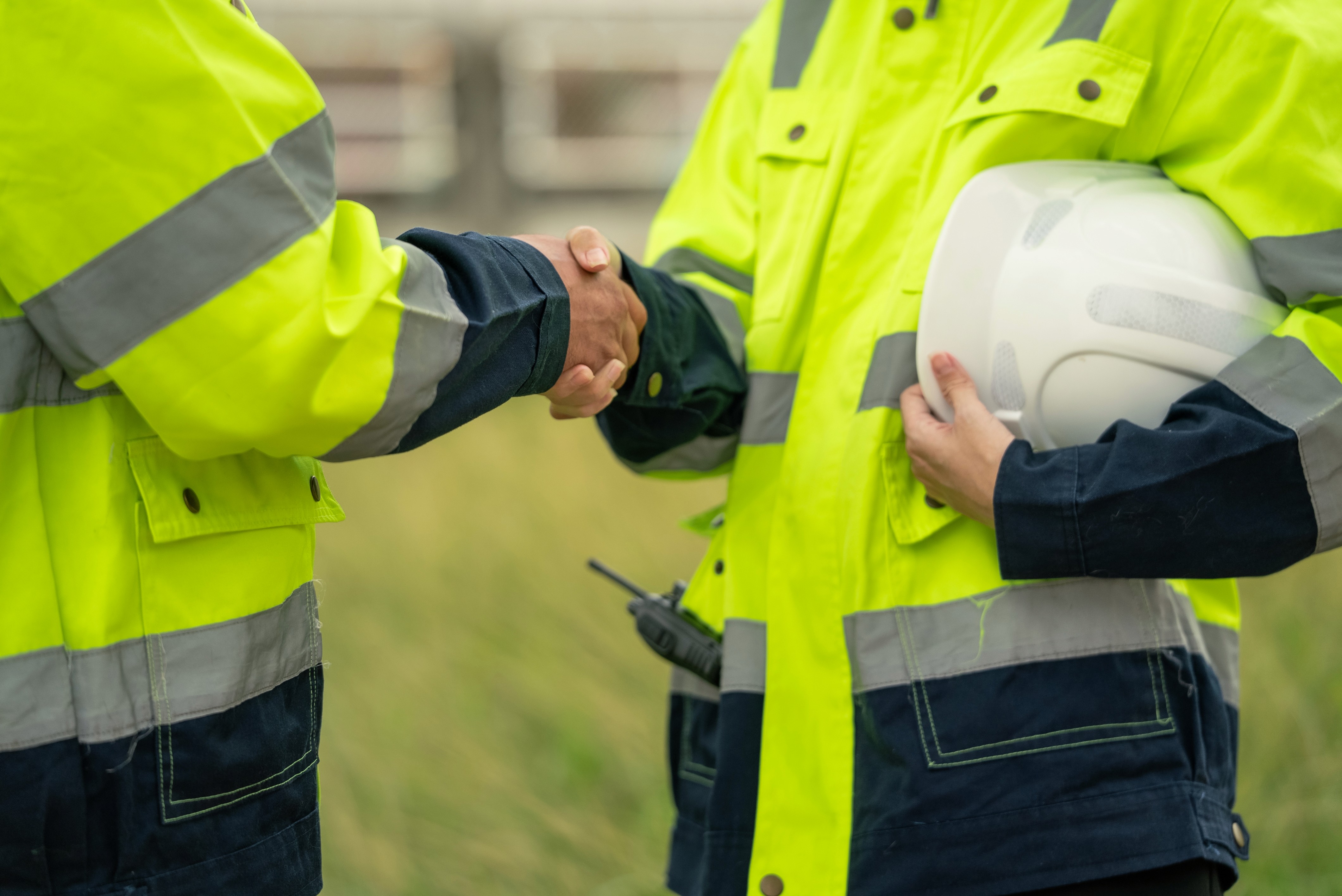 two men shaking hands in high vis jackets