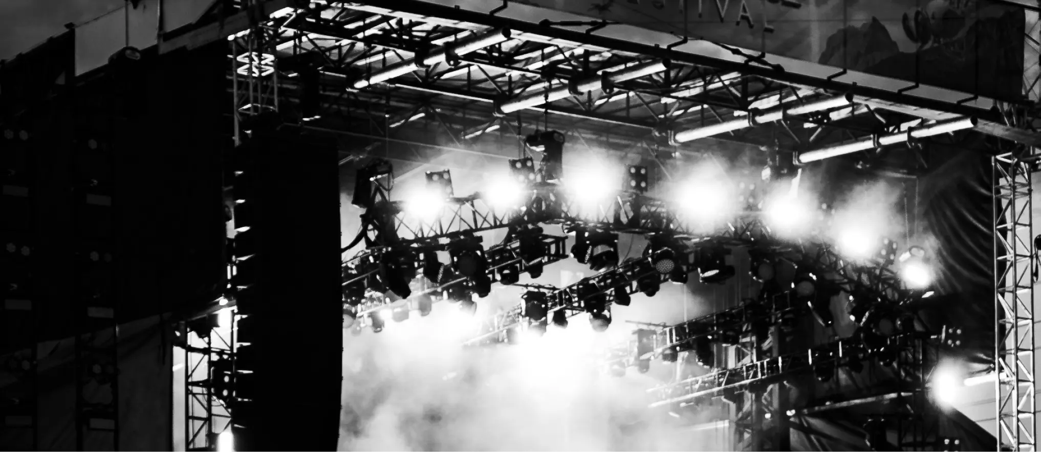 A bustling music concert, enhanced by a light show, takes place on an open-air stage at a vibrant music festival.