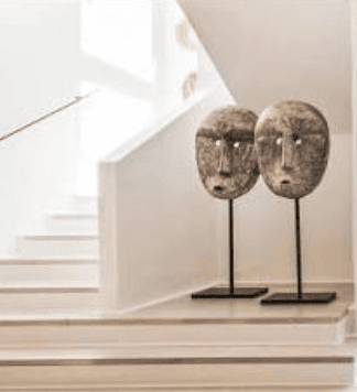 Two sculptural objects on stands beside a white staircase for the styling and handover stage.