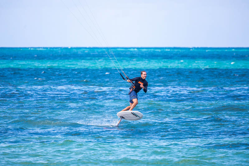 Kite surfer hydrofoils over turquoise water