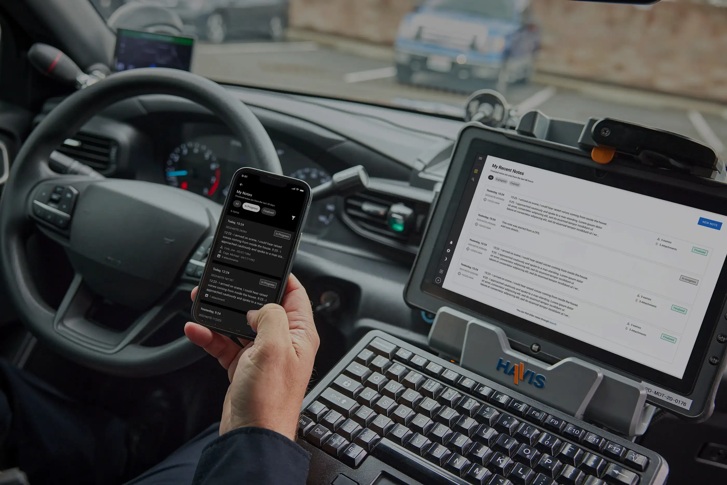 Alt Text: A police officer in a patrol car holding a mobile phone and viewing a laptop, both synced to the Digital Notes product showing a chronological list of the day's entries.