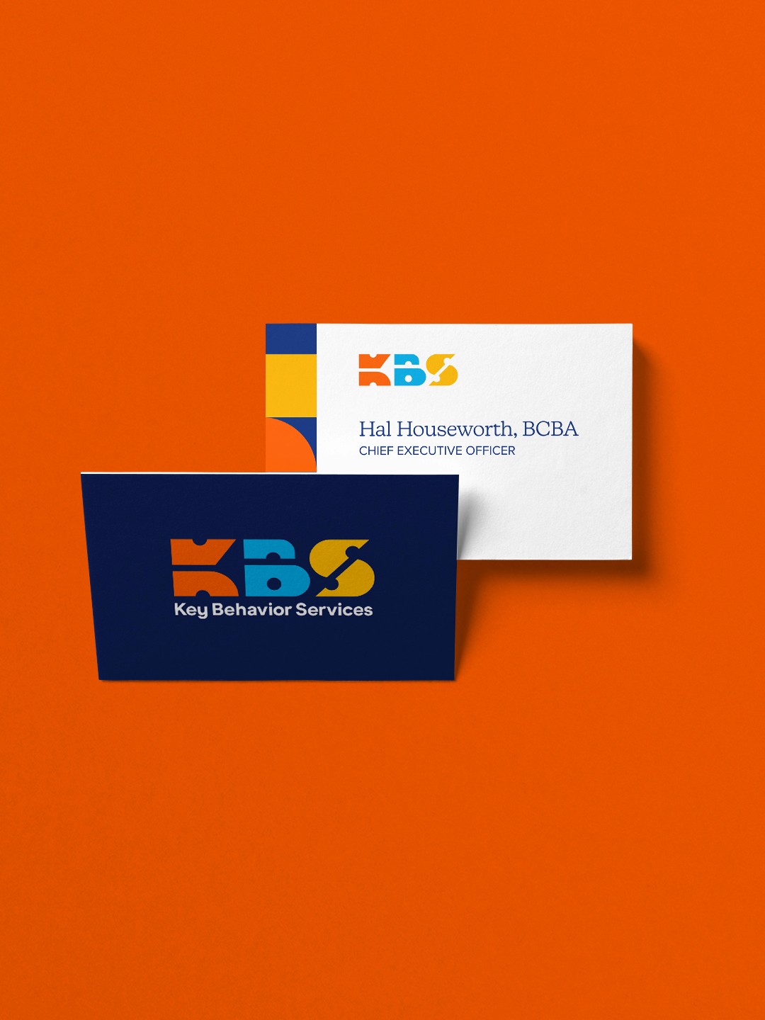 Front and back of KBS business card design on an orange background.