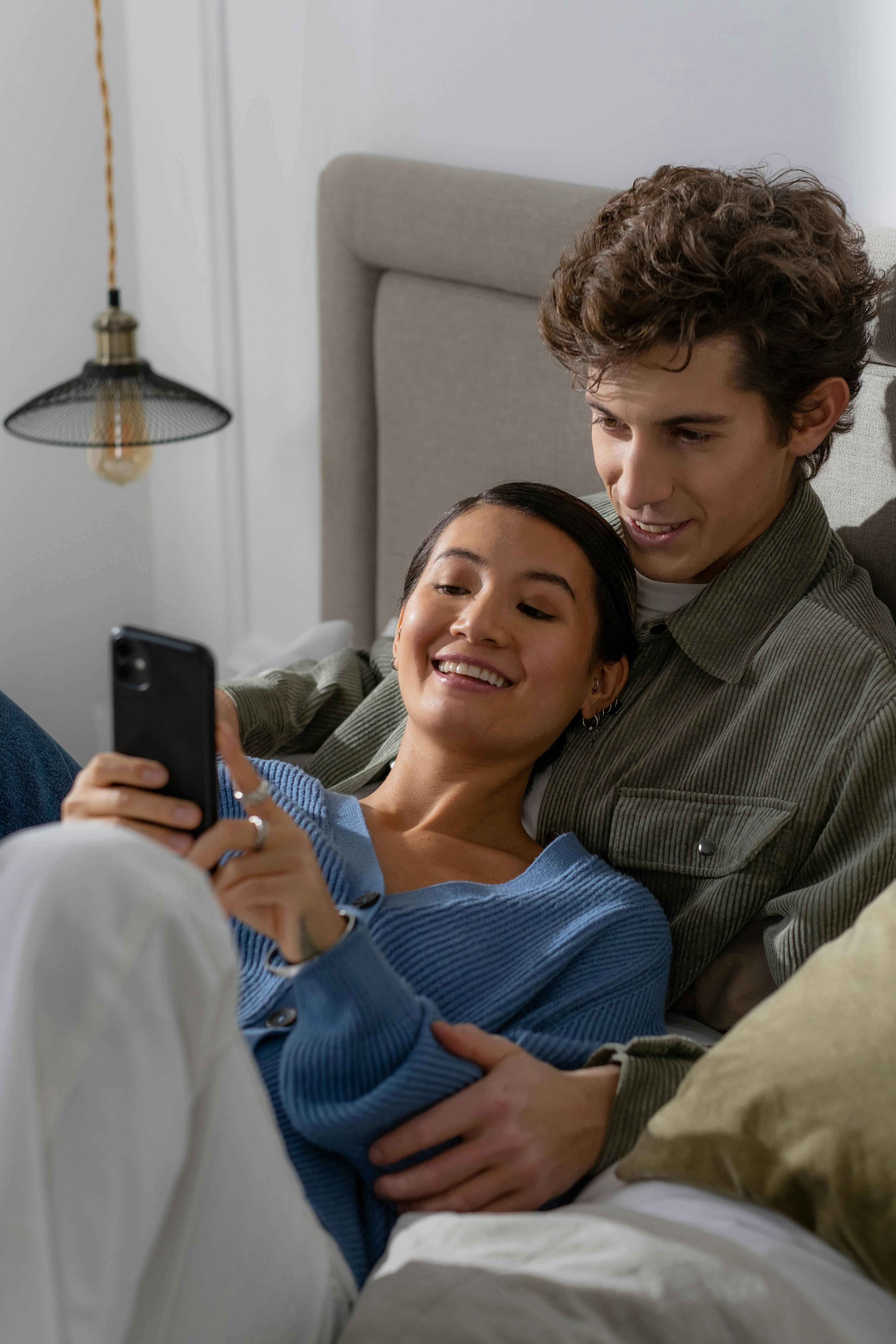 woman holding a phone and man looking at the phone. both are smiling