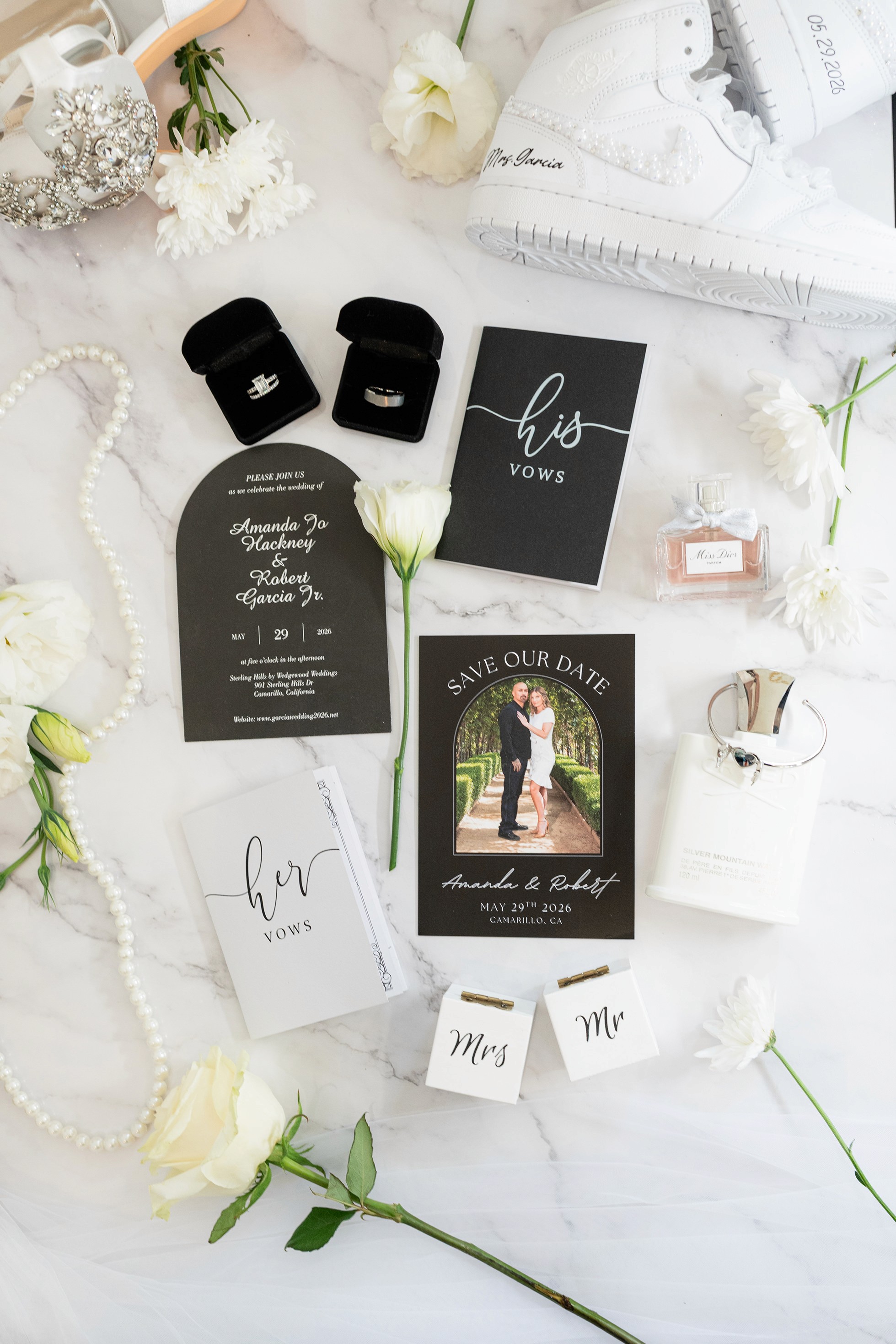 Wedding flat lay with rings vow books and Miss Dior perfume