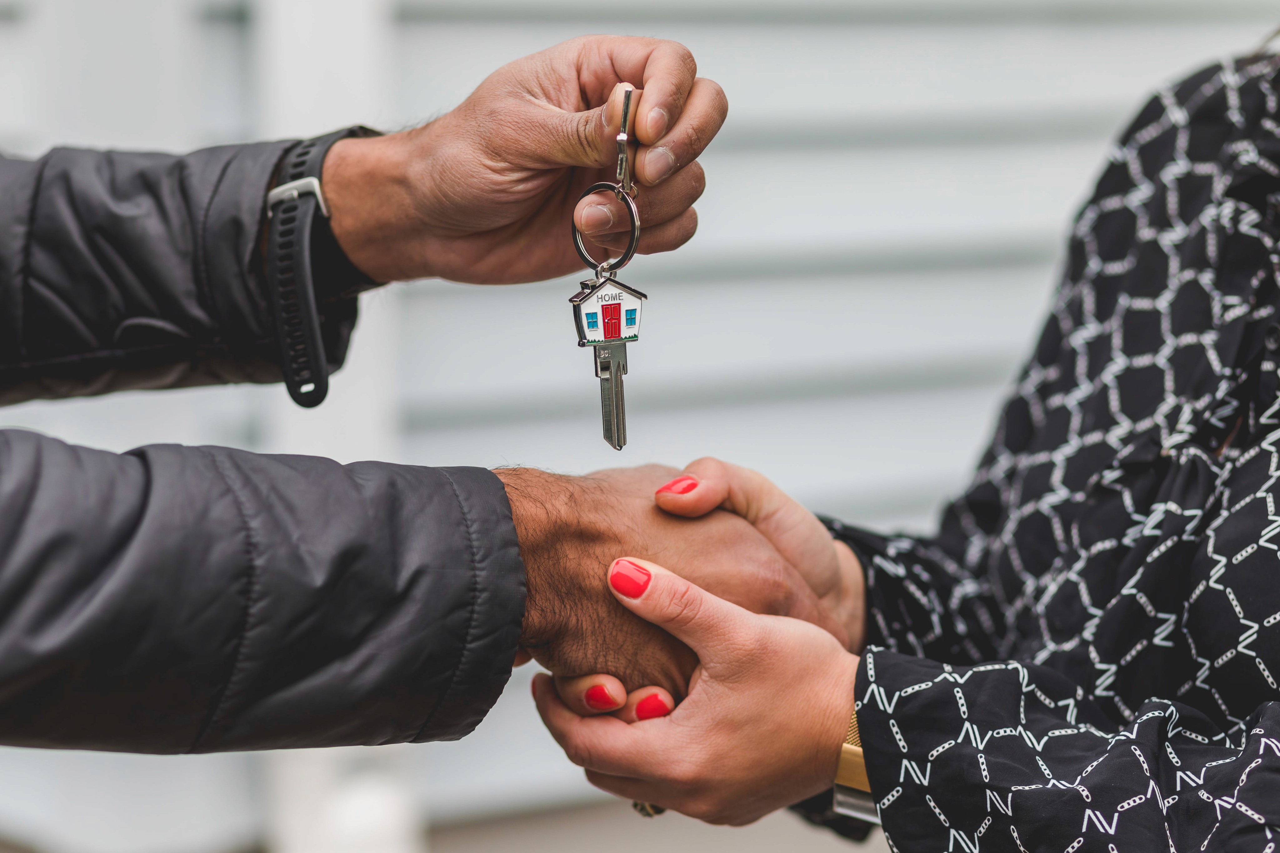 Two people shaking hands, with one holding a key over their shook hands