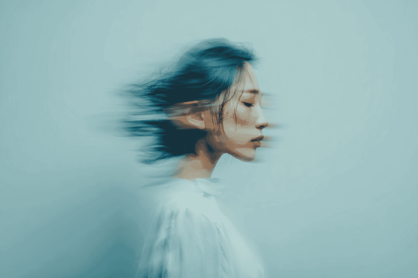 A blurred profile of a woman against a light blue background. Her hair and features are motion-blurred, conveying a dreamy, serene atmosphere.