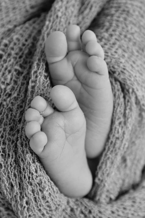 Black and white close-up of baby soles on a knitted blanket