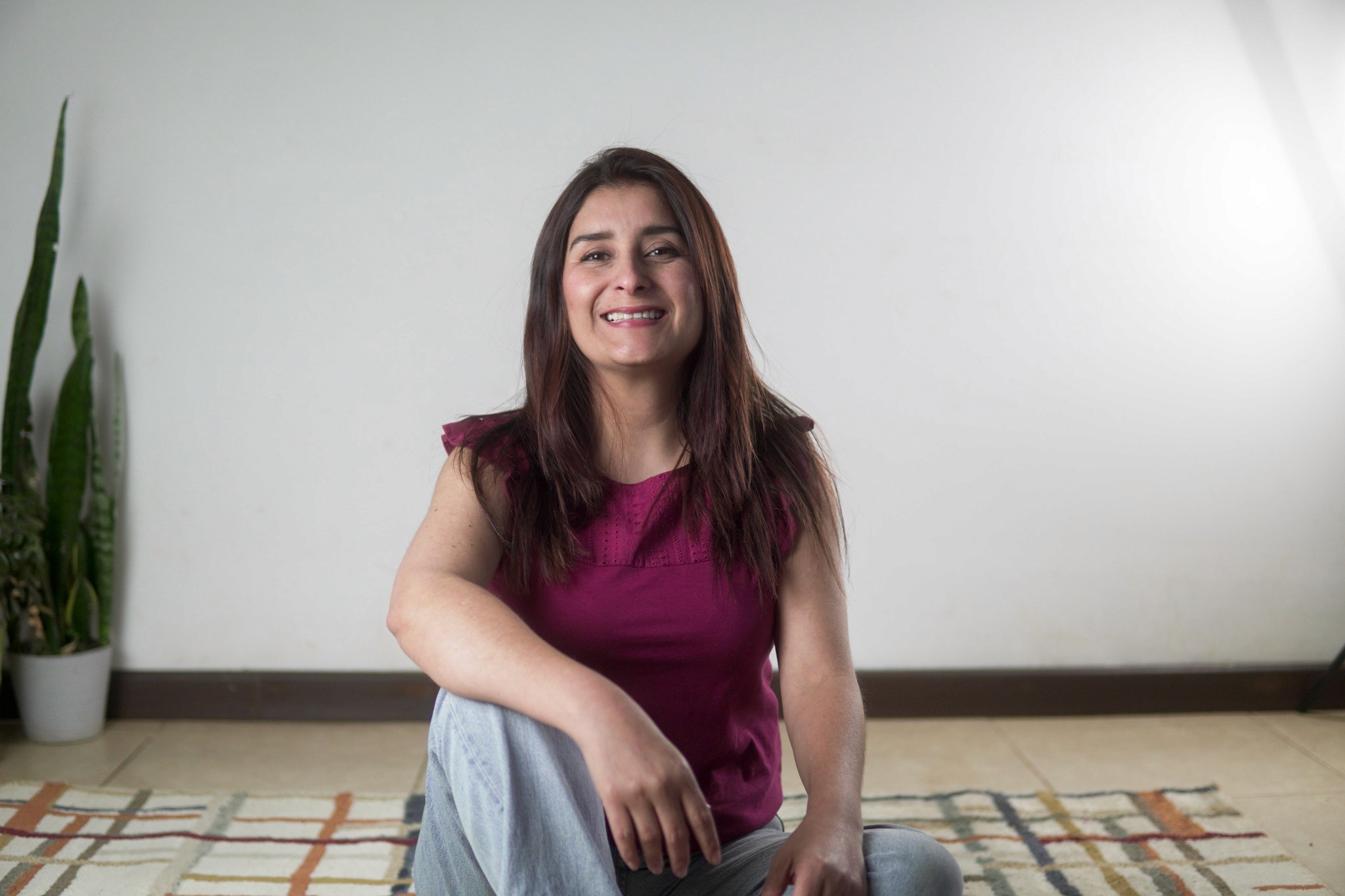 A person with curly hair sits at a desk, working on a laptop in a cozy, well-lit environment.