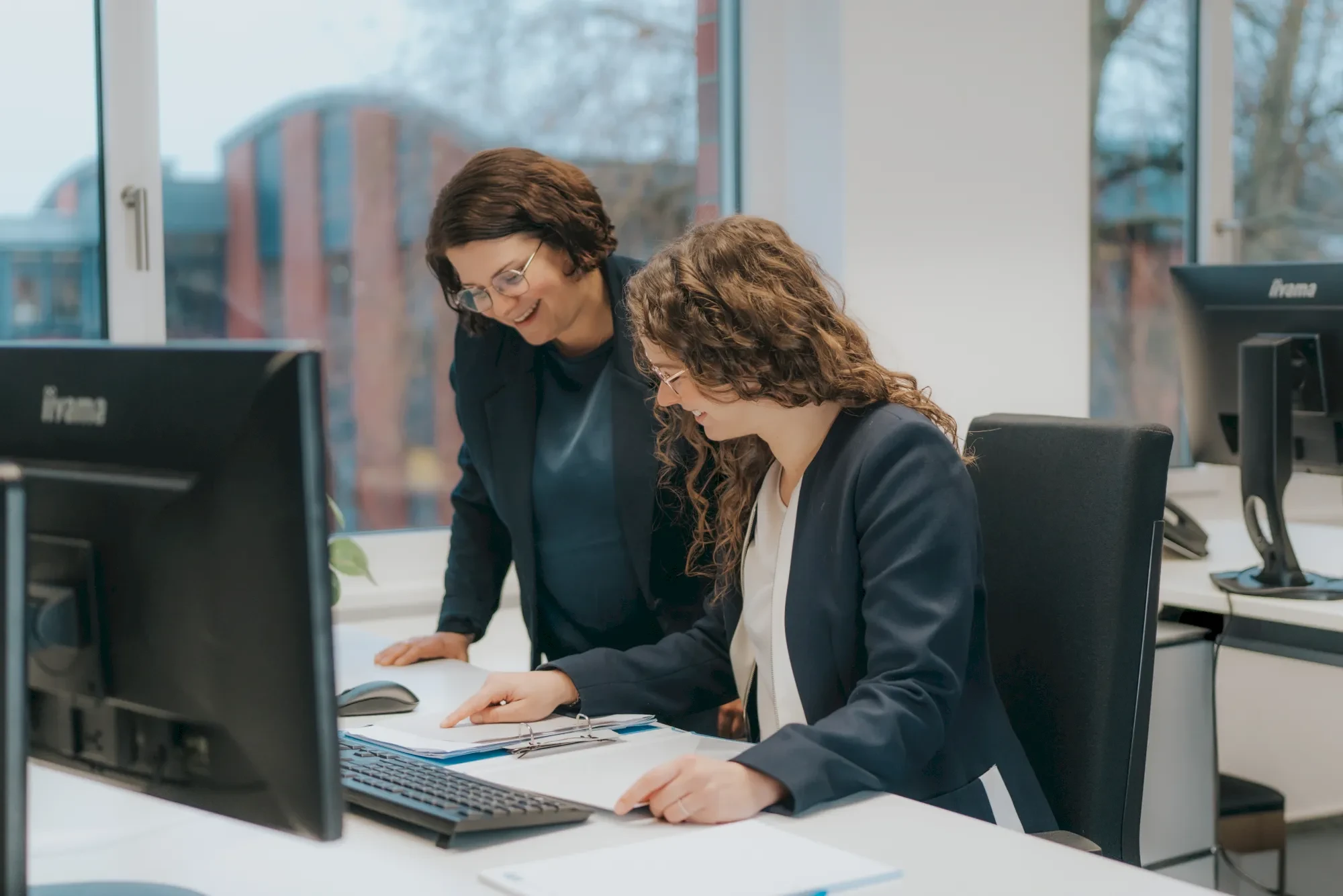 Zwei Frauen arbeiten zusammen an einem Computer. Büro, Zusammenarbeit, Teamwork.