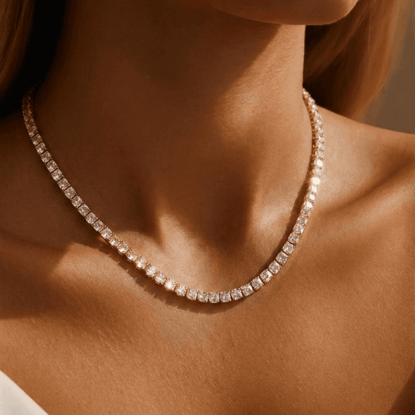 Close-up of a diamond necklace on a model wearing a white top.