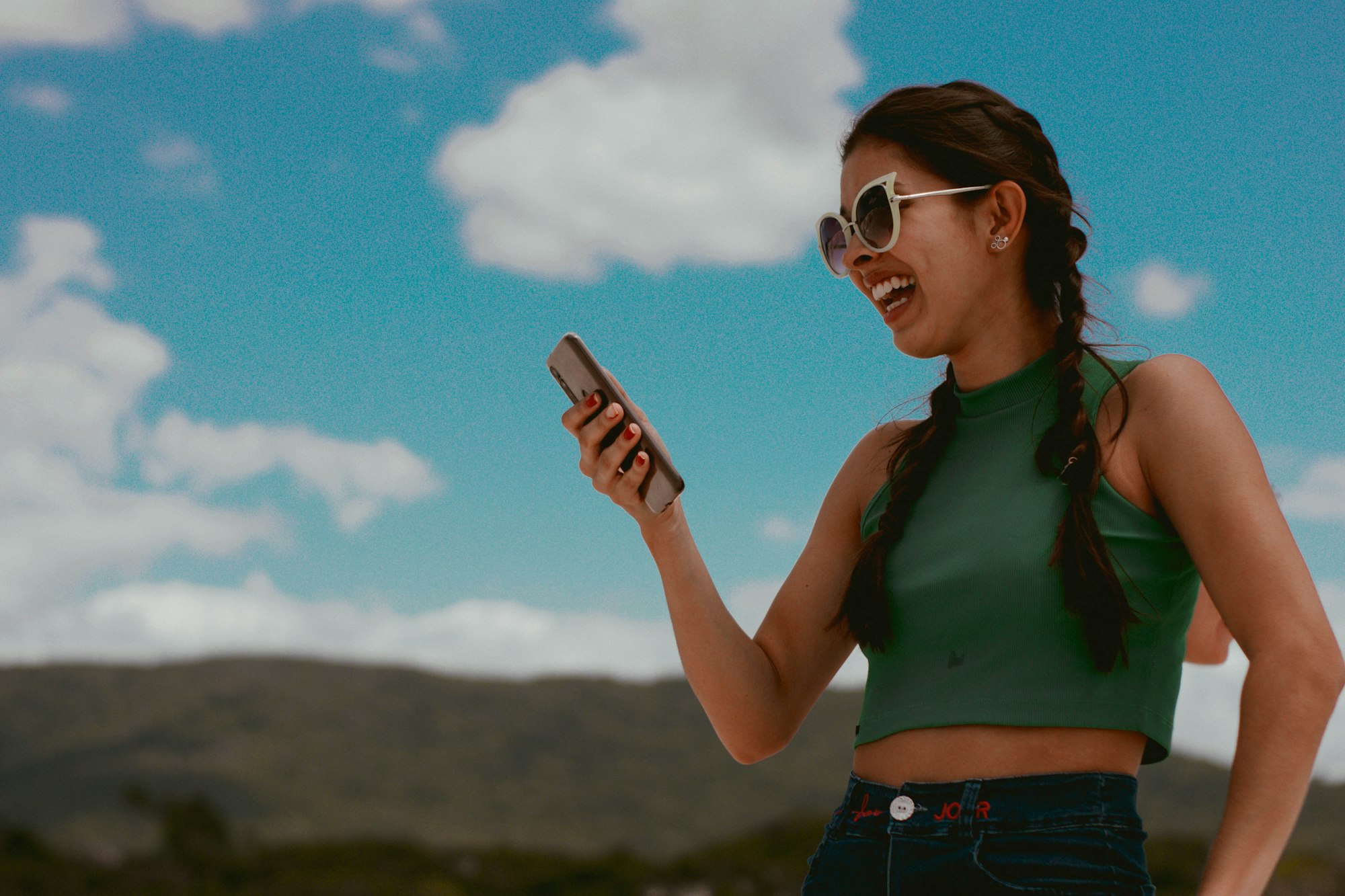 woman holding phone while smiling during daytime
