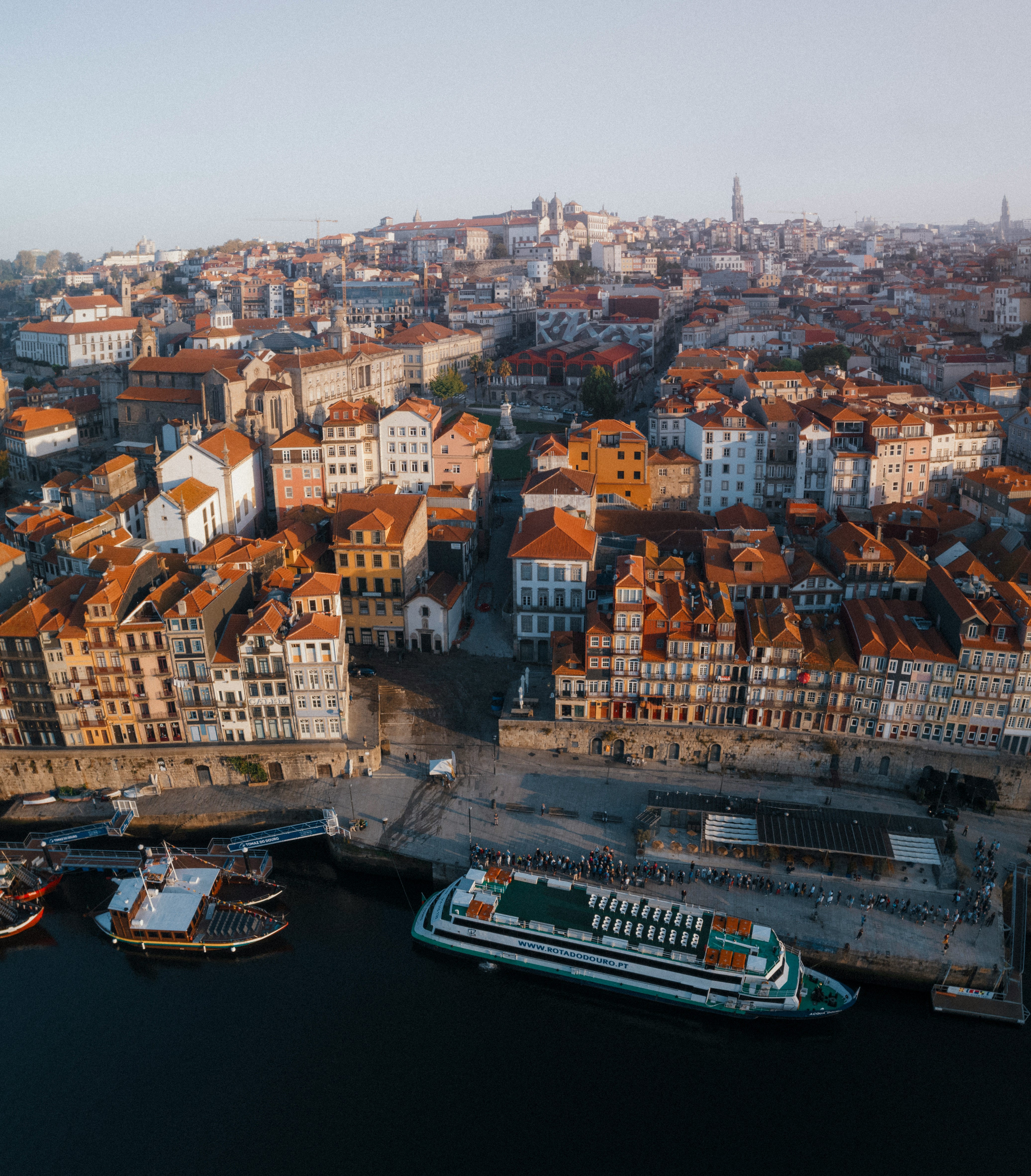 Aerial view of city buildings along a river with boats.