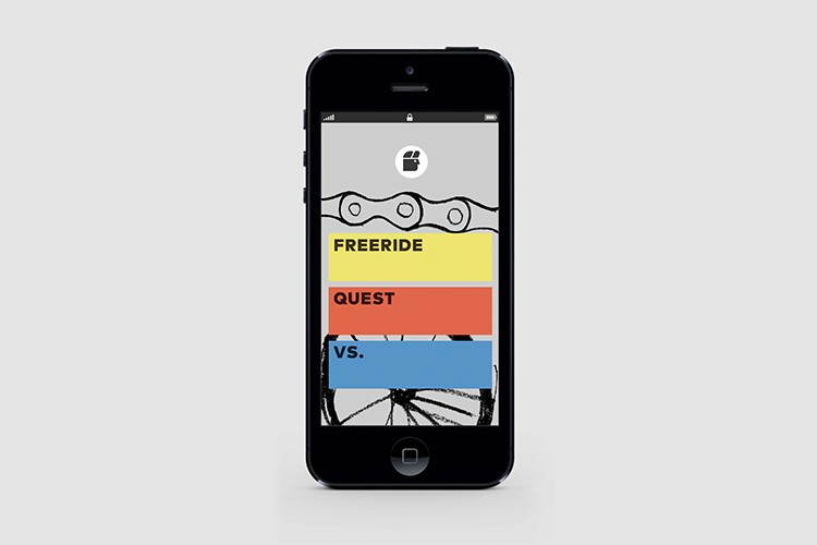 A black iPhone displays a screen showing a bicycle chain graphic at the top. Below it, the text "FREERIDE" is displayed in yellow, followed by "QUEST" in red, and "VS." in blue. The background is light gray.