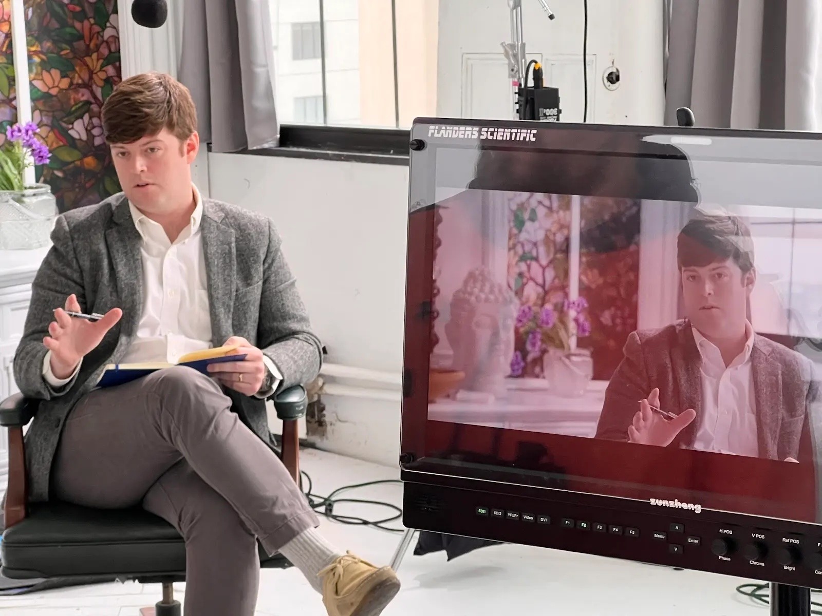 Host filmed with a production monitor on the office set