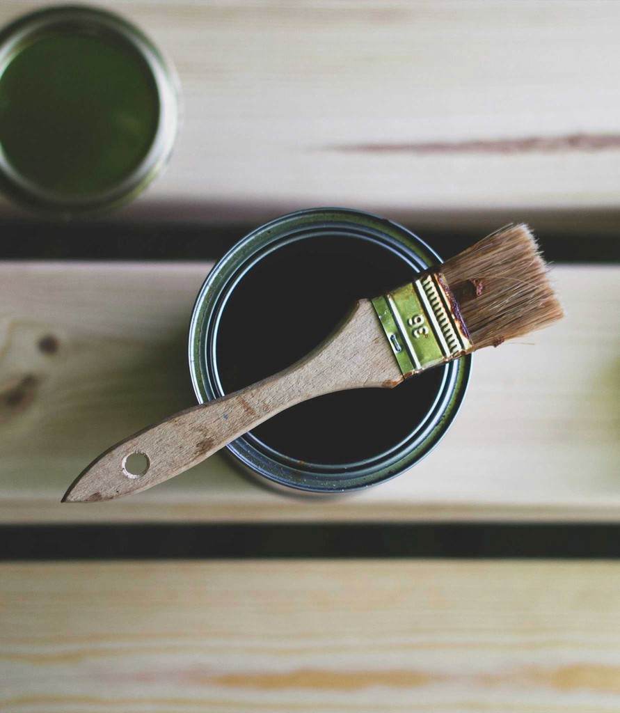 A small paintbrush sitting on top of a paint tin