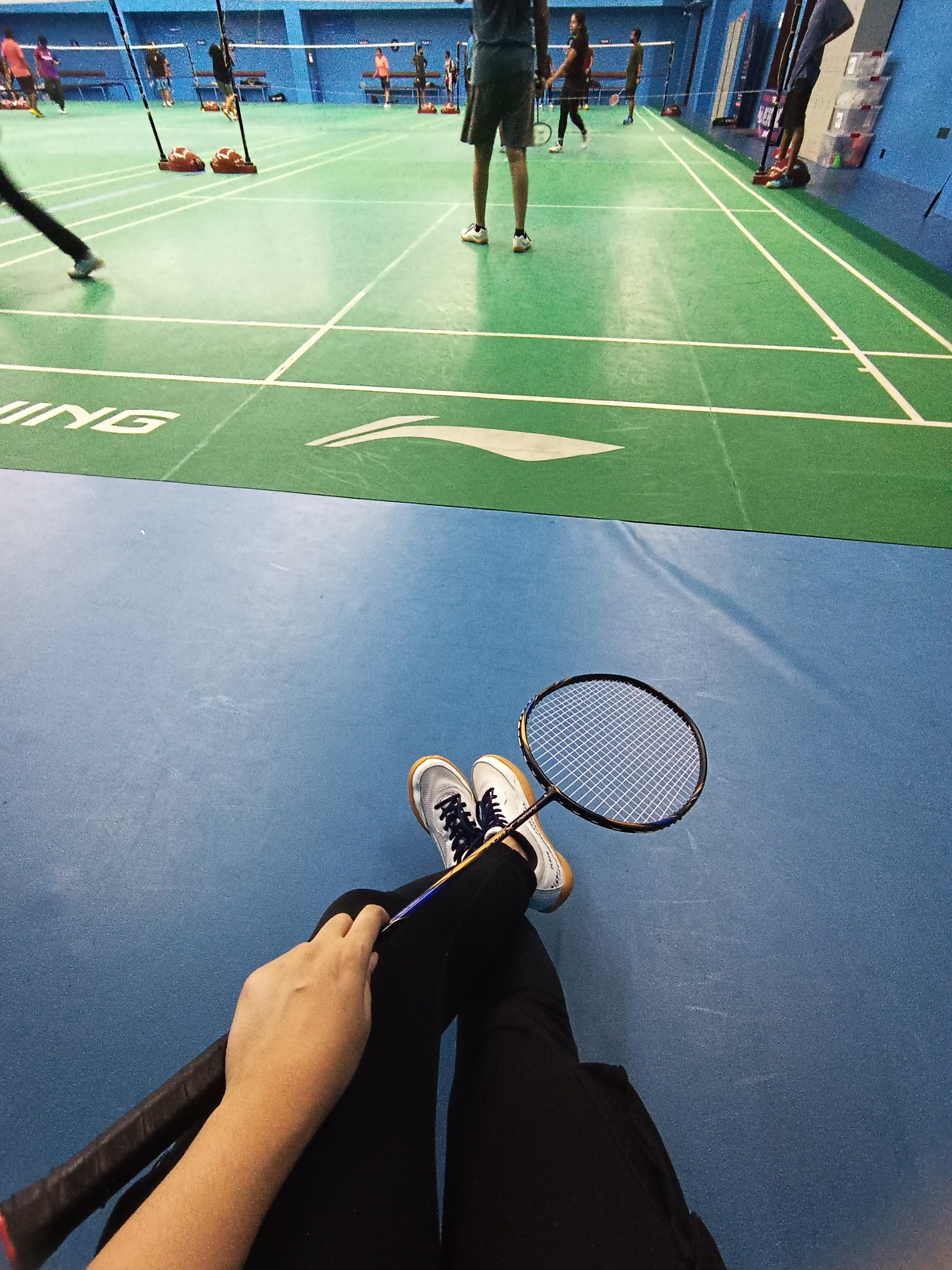 Person holding a racket in a badminton court