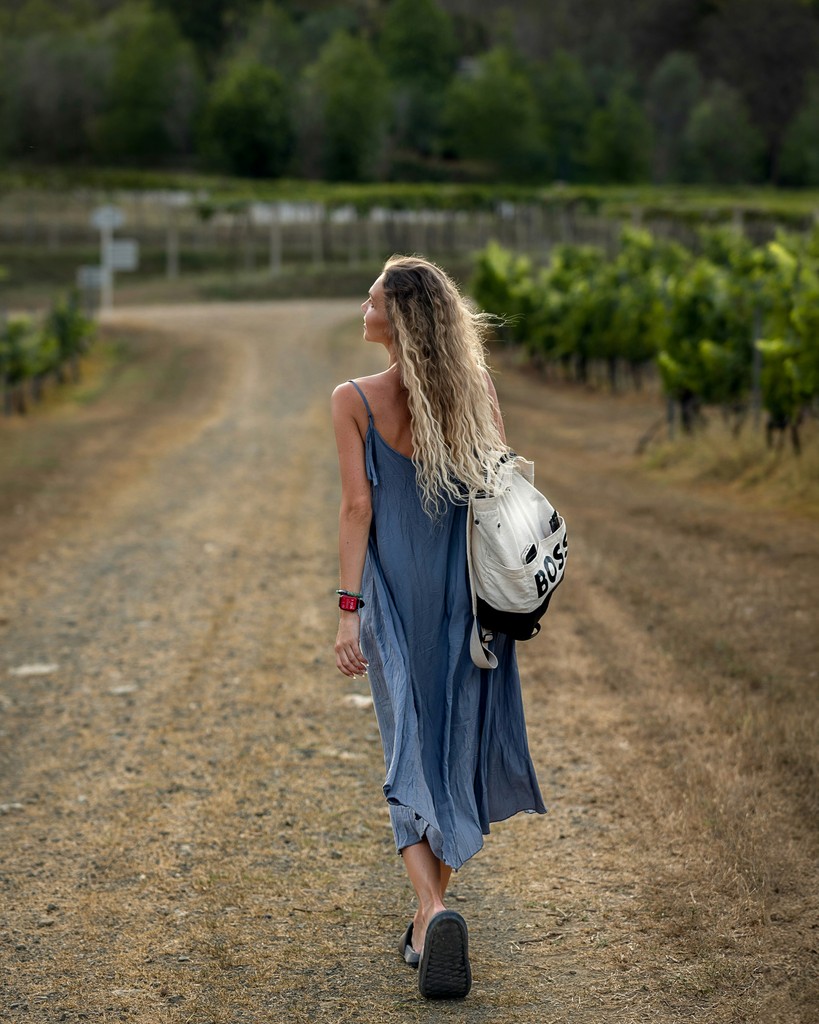 a woman with a backpack walking down a dirt road