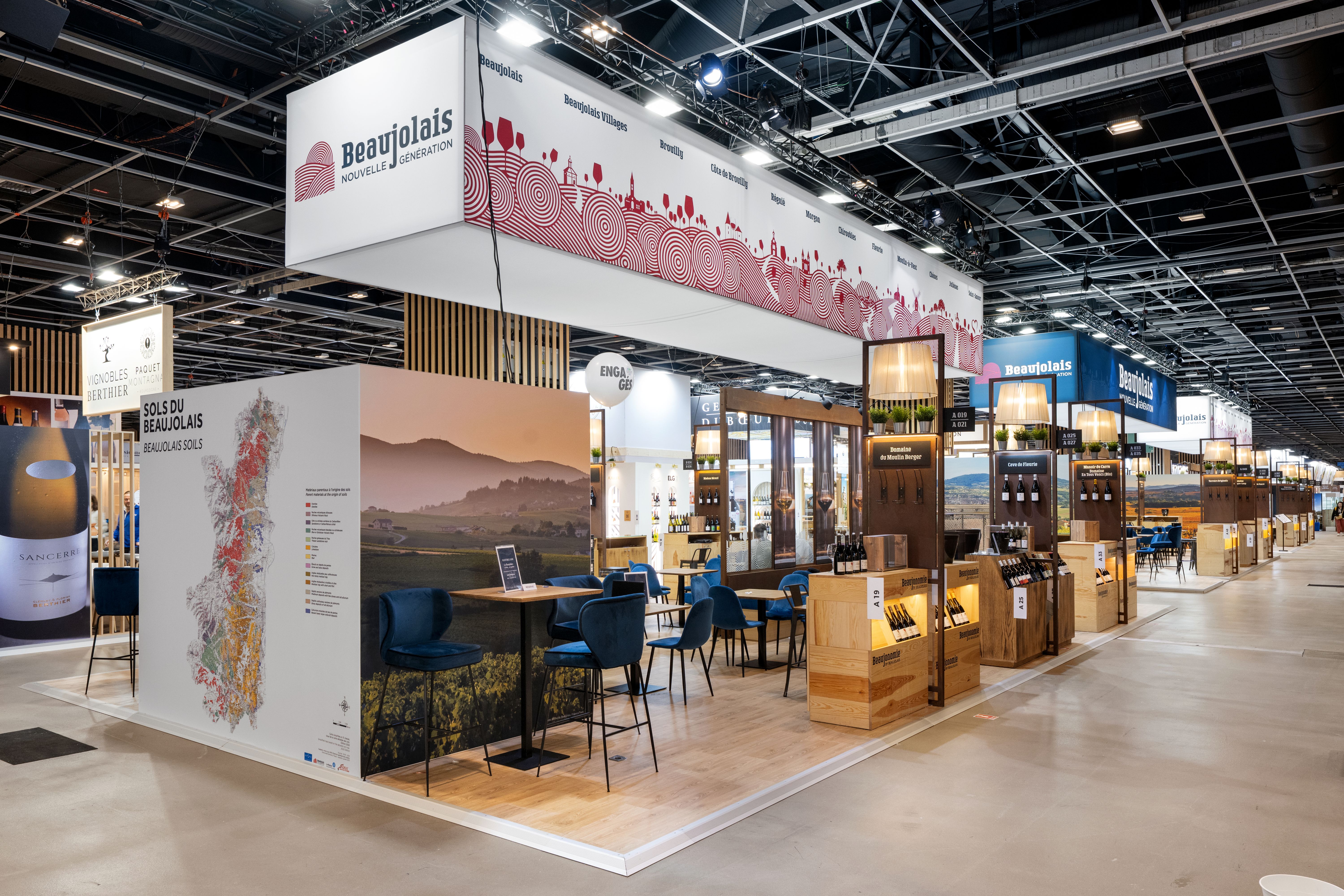 Stand Inter Beaujolais Wine Paris 2026 réalisé par Expace – vue frontale avec visuels vignoble grand format, comptoir dégustation bois naturel et signalétique appellations beaujolaises