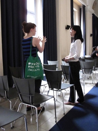 woman with a green tote bag talking to another woman