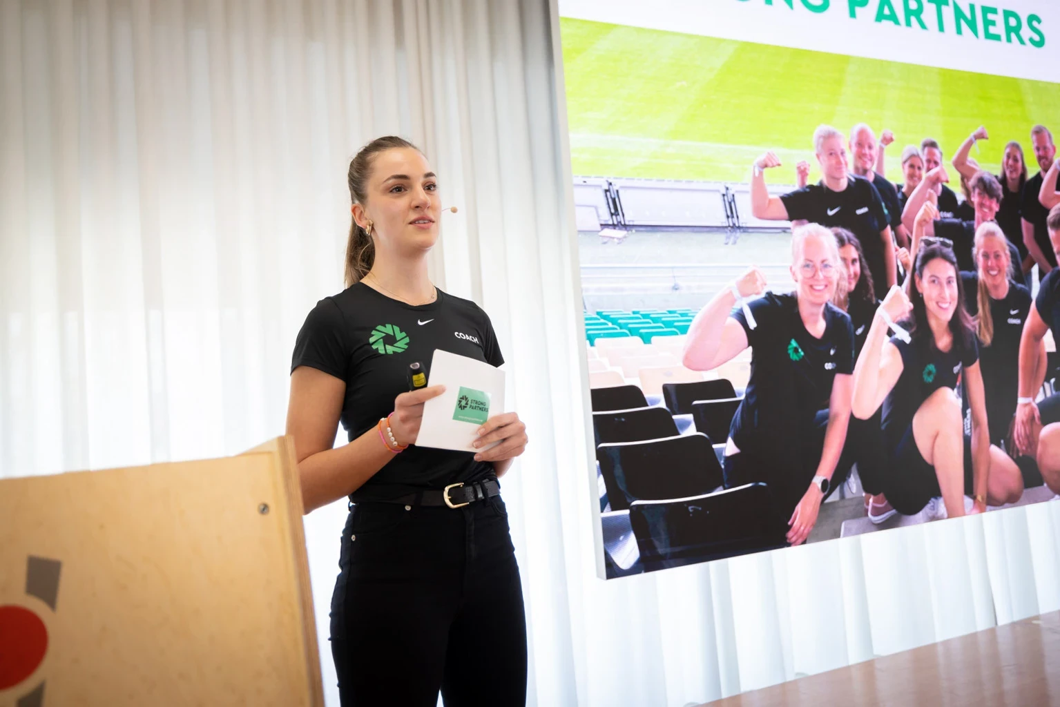 Frau im Strong Partners T-Shirt steht auf einer Bühne