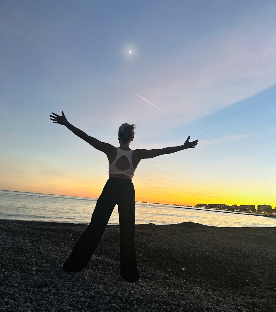 mujer con brazos abiertos frente al mar