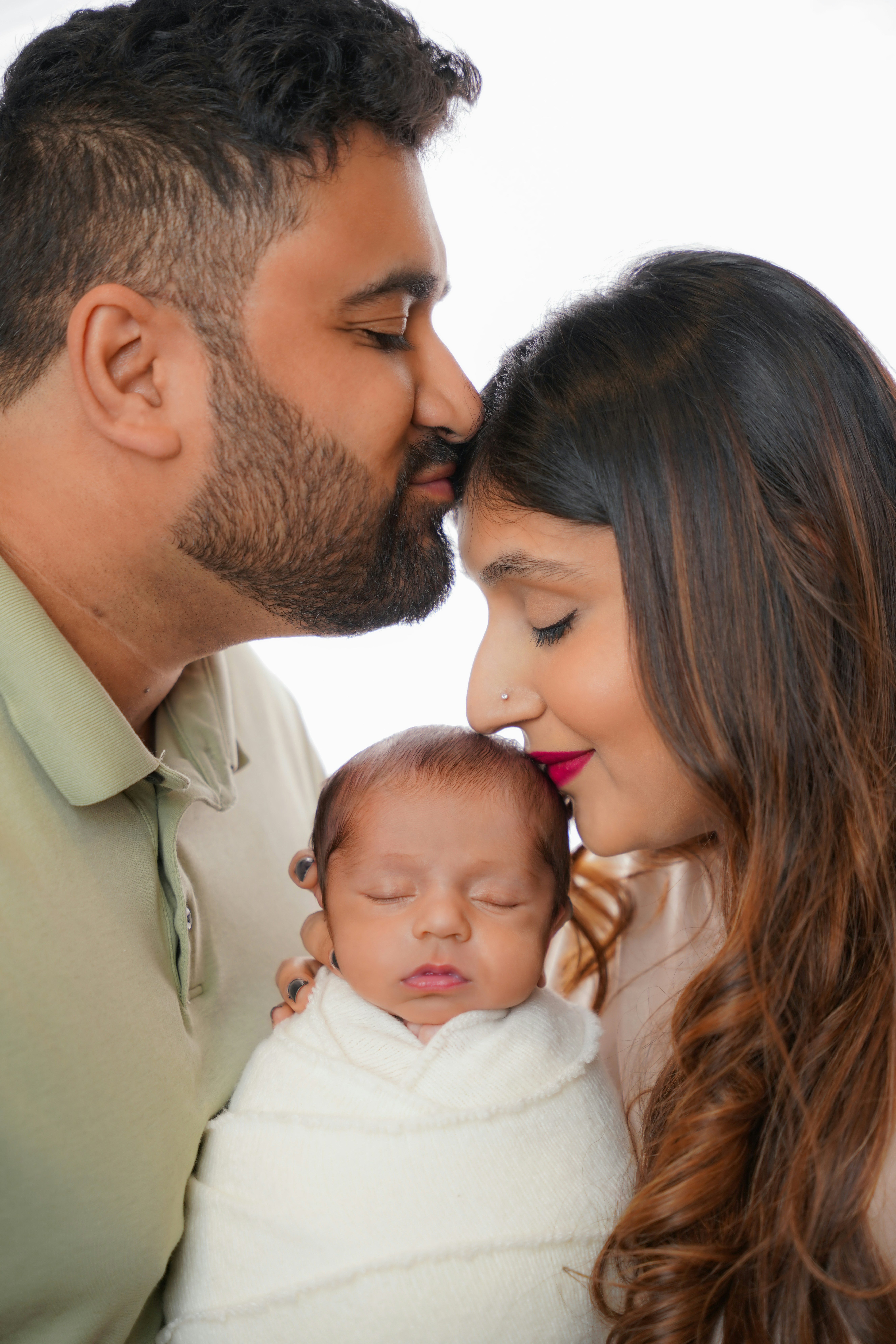 Parents kissing their newborn baby