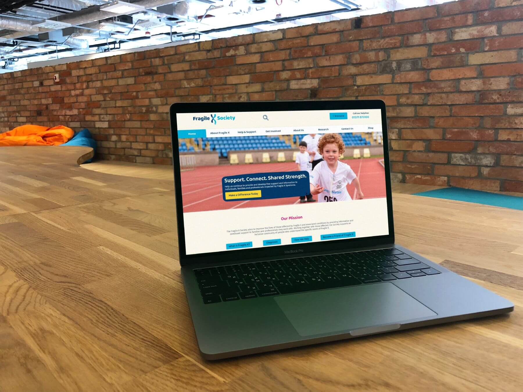 New Fragile X Society landing page, in room with wooden floor and brick backdrop