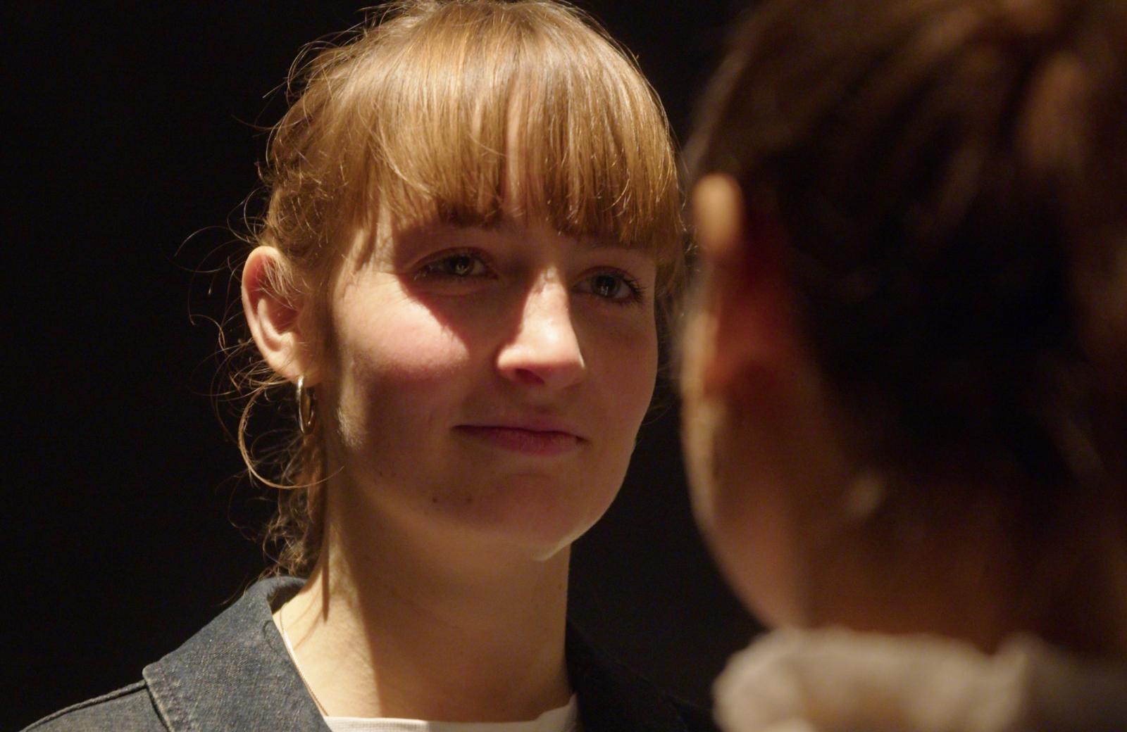 Woman in pink leather jacket crouching outdoors at night
