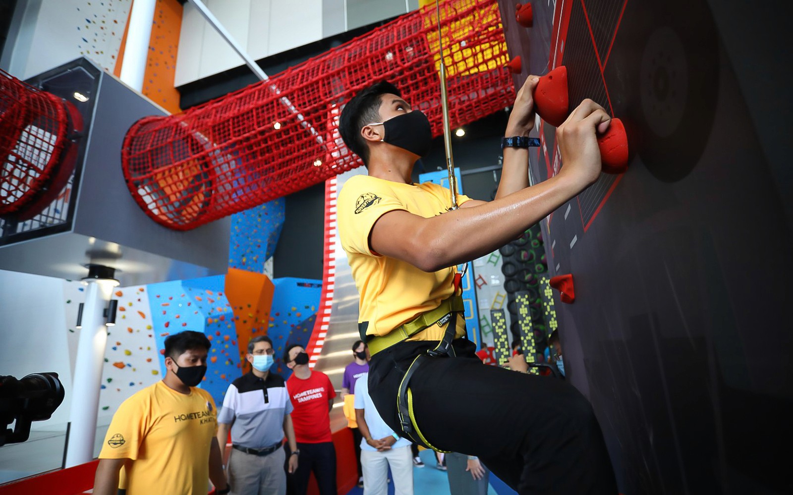 在探险总部的室内墙上攀岩,墙上方设有红色网状隧道。