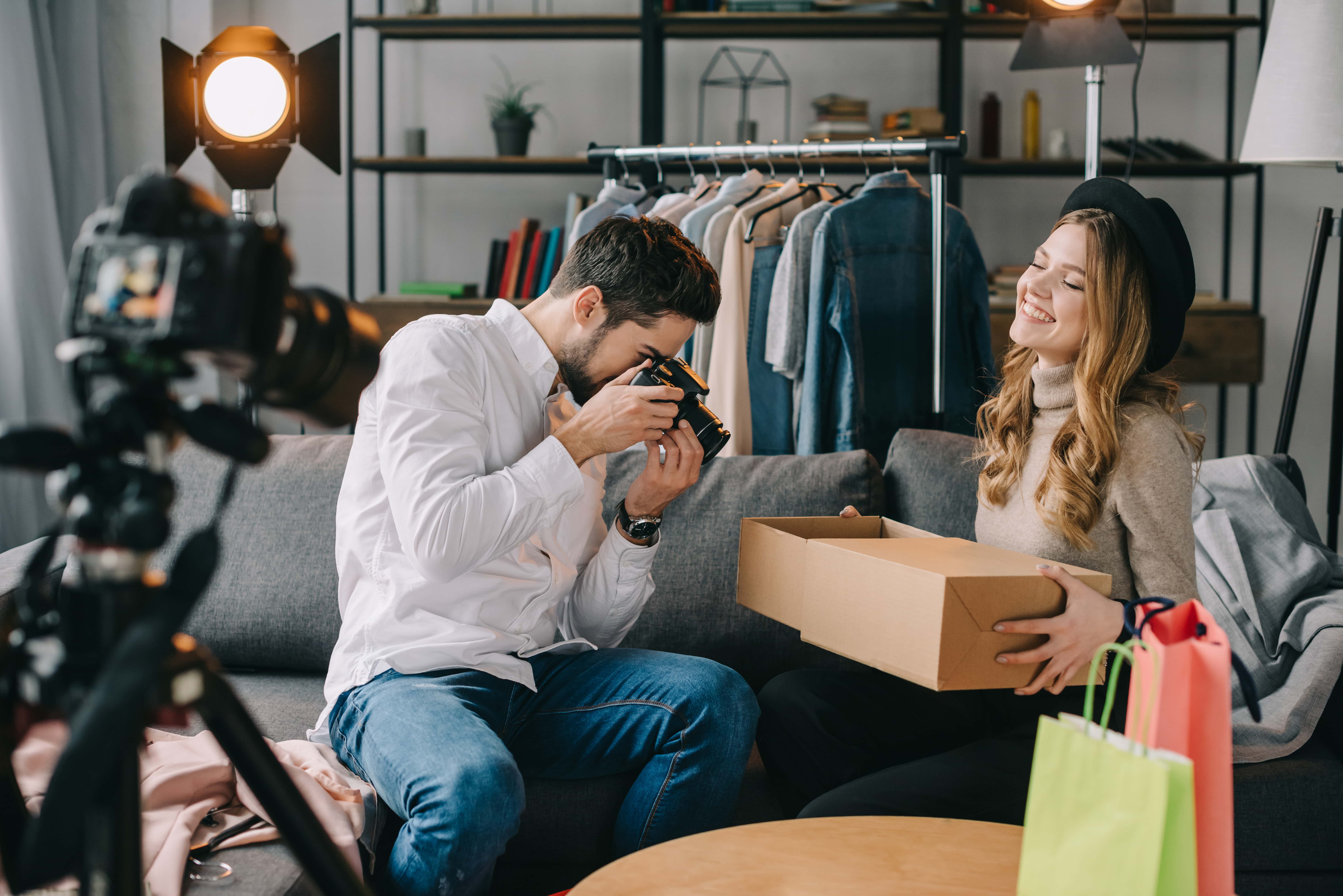 photographer shooting fashion blogger with new clothes in box