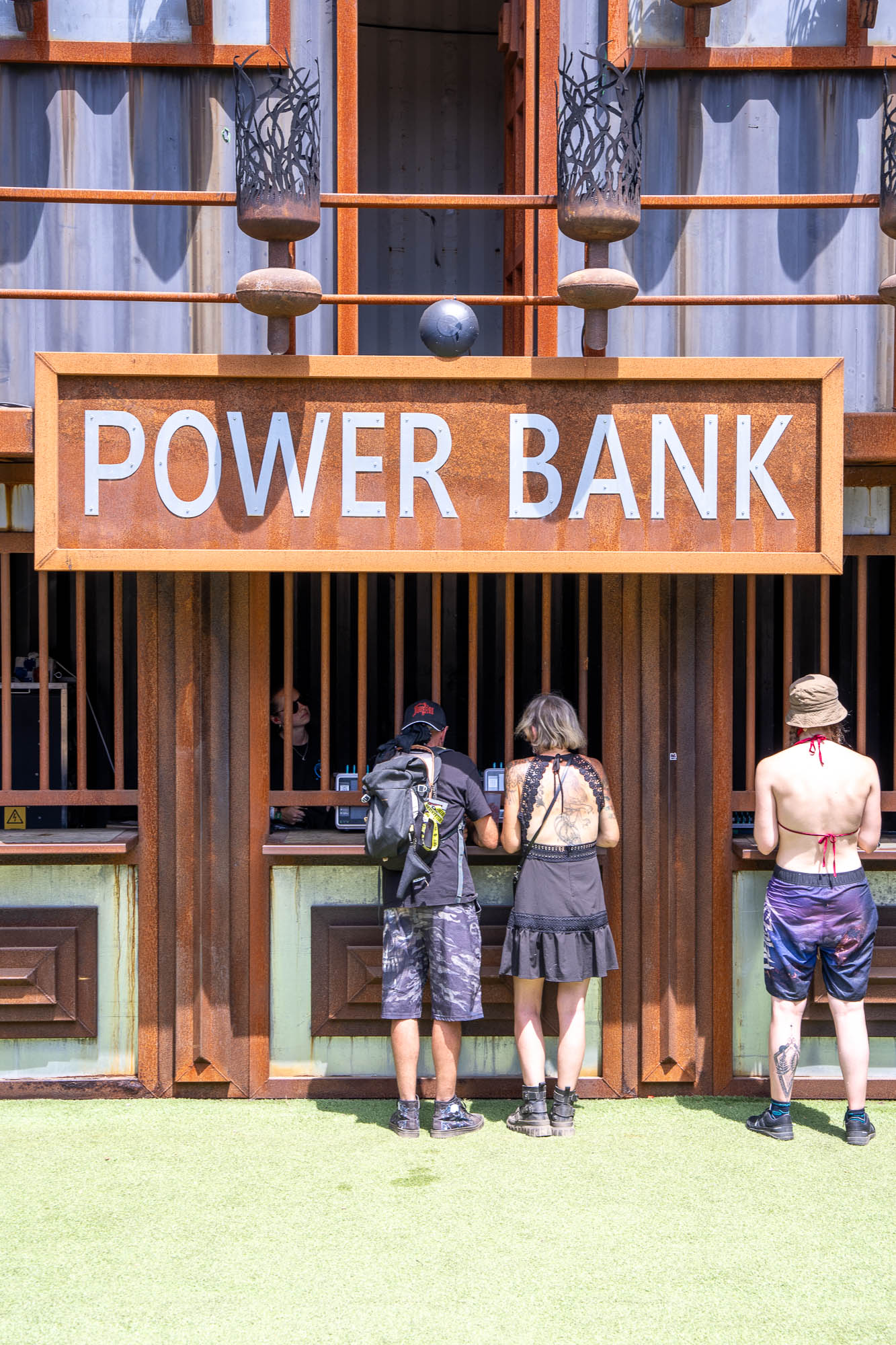 Trois festivaliers rechargent leurs téléphones au comptoir Power Bank du Hellfest 2026