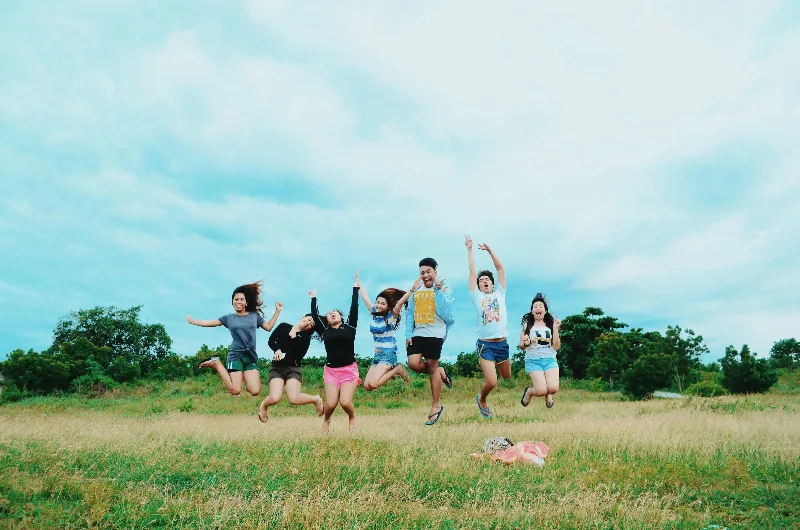 KId's jumping up on a grass field.